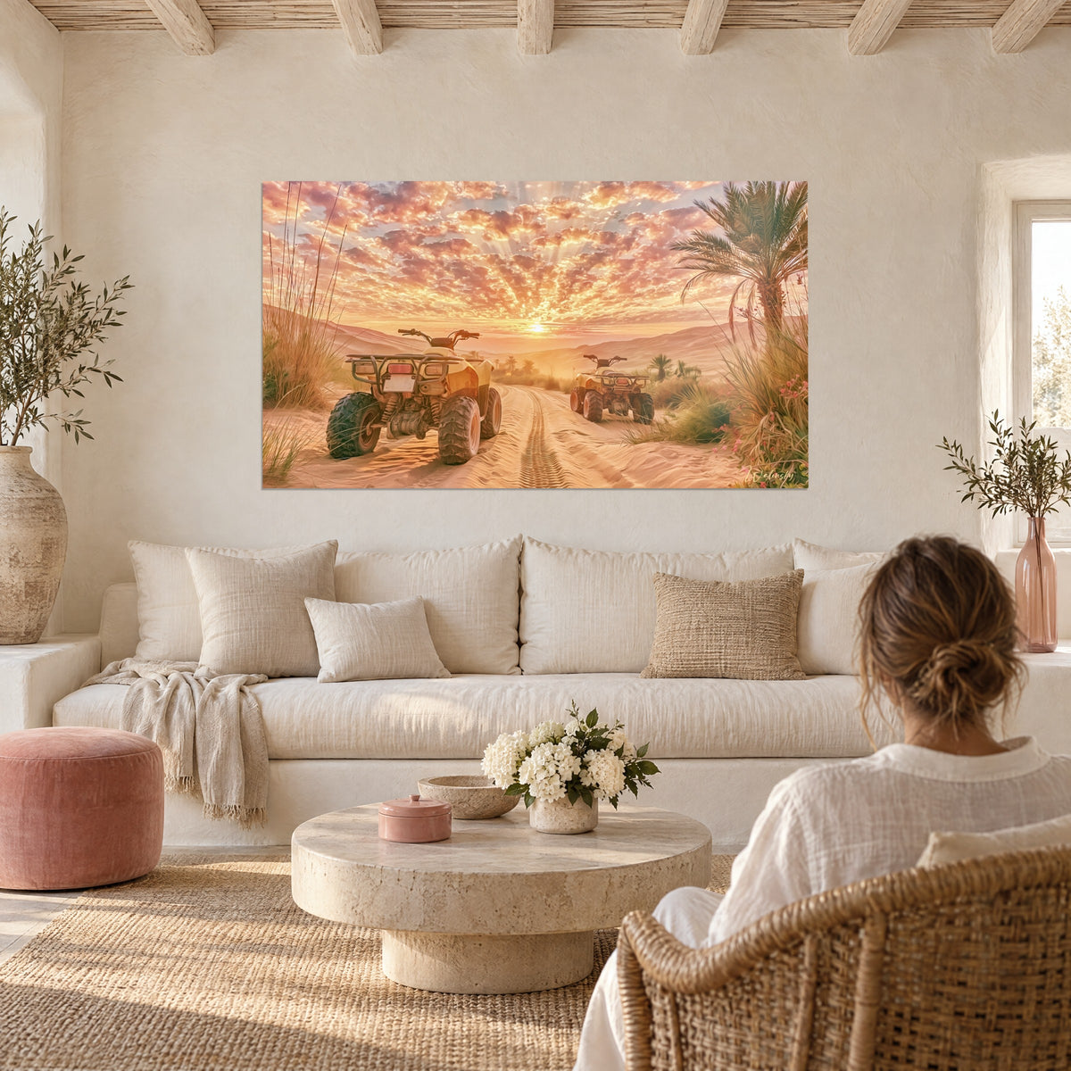 Wall art yellow quad bikes parked on golden sand, pink sun at the center of the clouds, woman seen from behind above a sofa in a bright living room