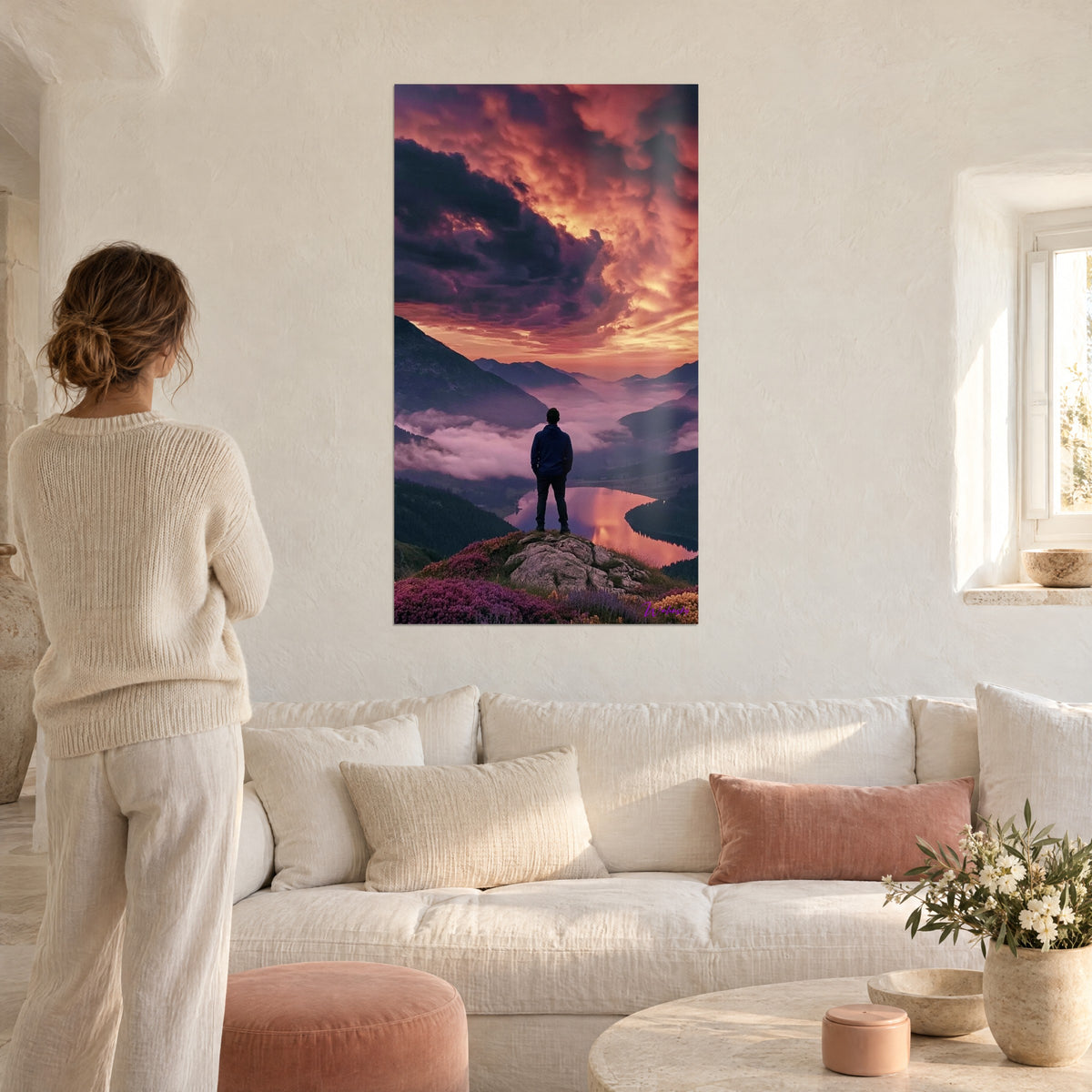 Tableau randonneur en veste bleue face aux nuages pourpres et orange, femme de dos, au-dessus d'un canapé dans un salon lumineux