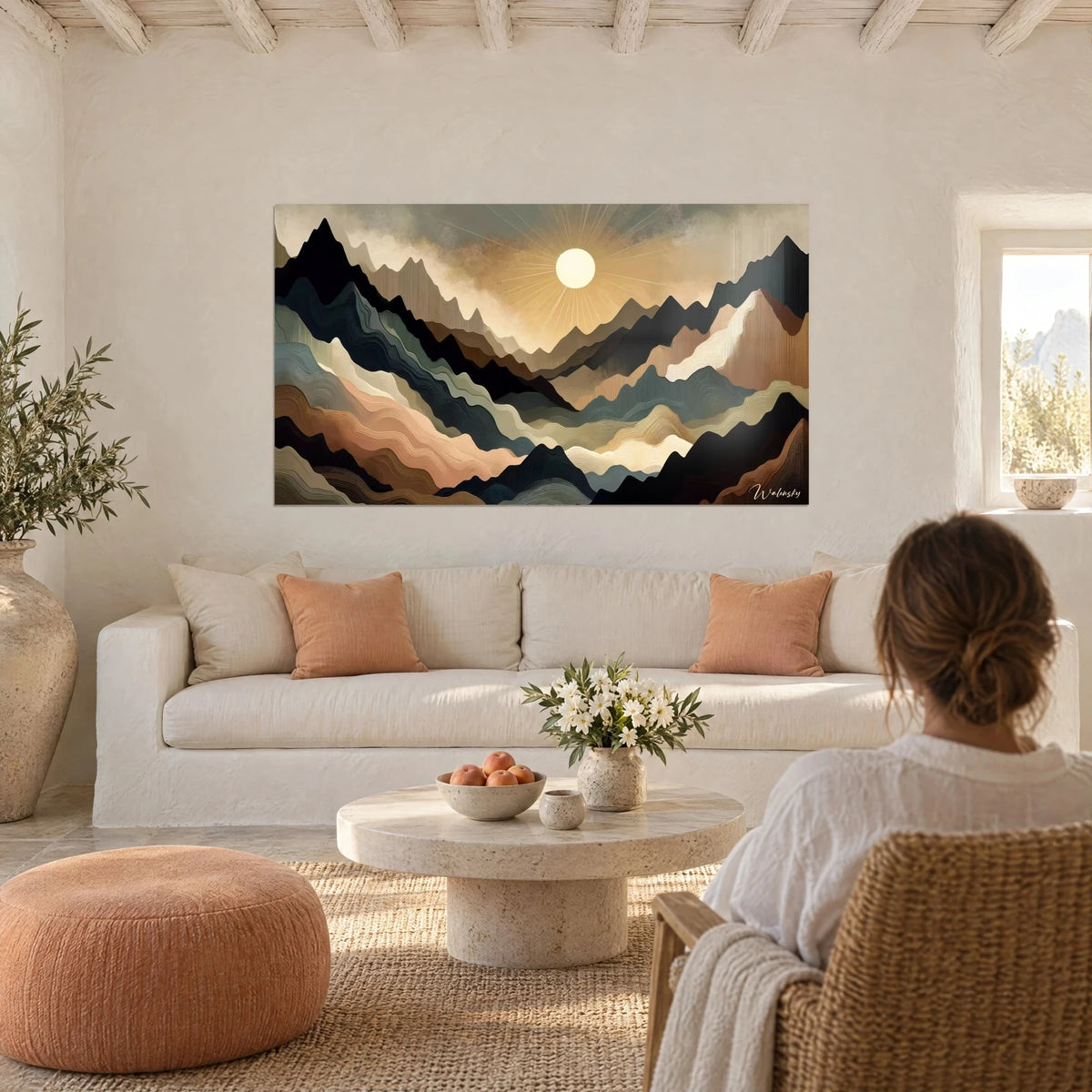 Wall art of a pale, radiant sun above black and ochre ridges, hung above a sofa in a bright living room