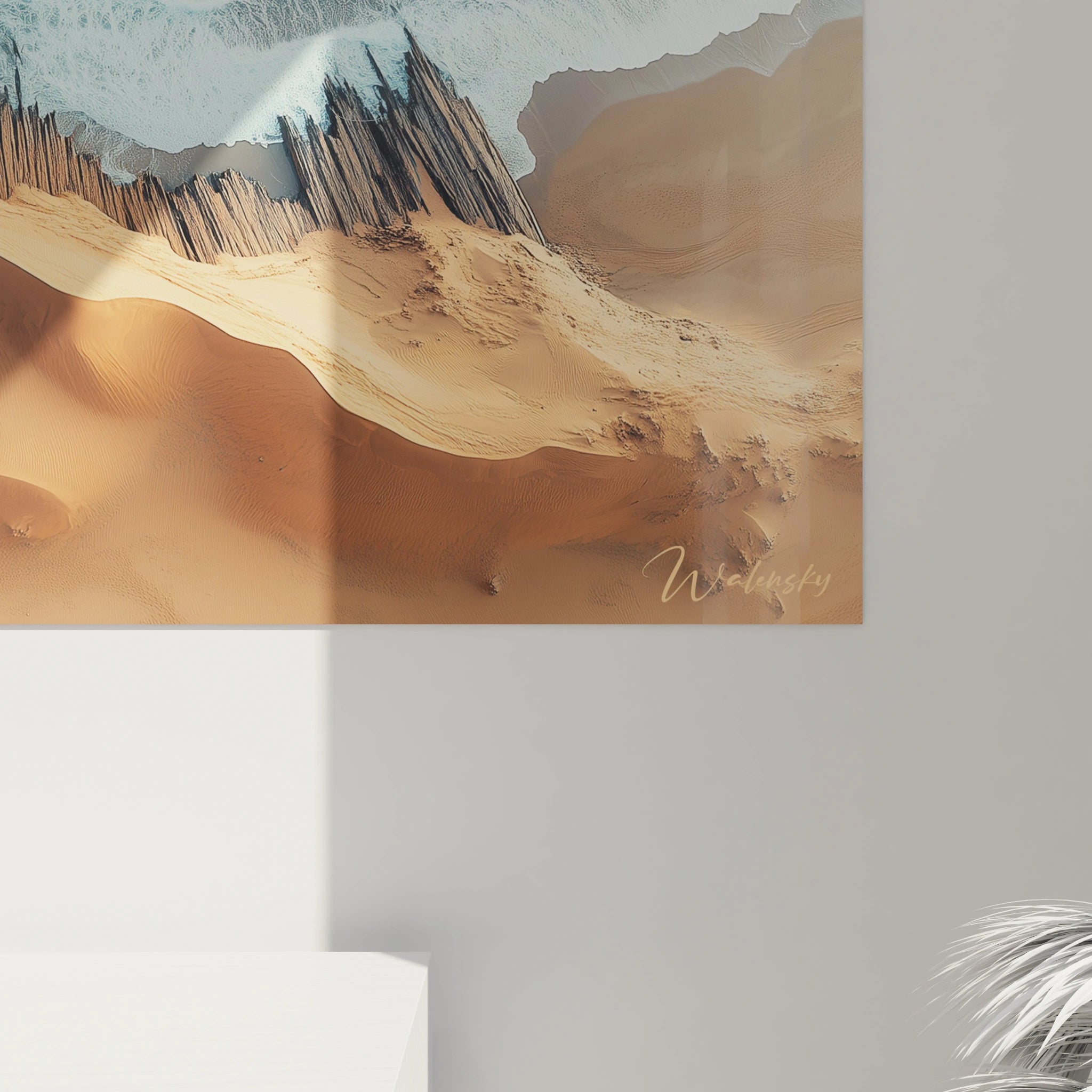 Un tableau plage désertique présentant la ligne de démarcation entre océan bleu écumeux et dunes dorées sculptées par le vent. Les barrières protectrices en bois créent une texture rugueuse contrastant avec la fluidité de l'eau et les ondulations douces du sable.