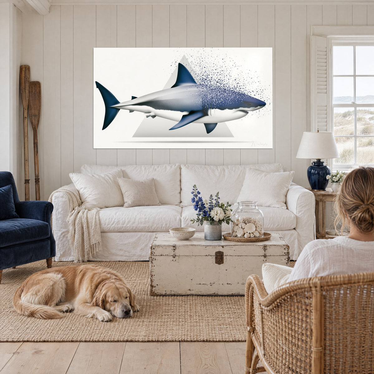 Schilderij grote witte haai in nachtblauw die afbrokkelt in driehoekige scherven, lichtgrijze driehoek, boven een bank in een lichte woonkamer