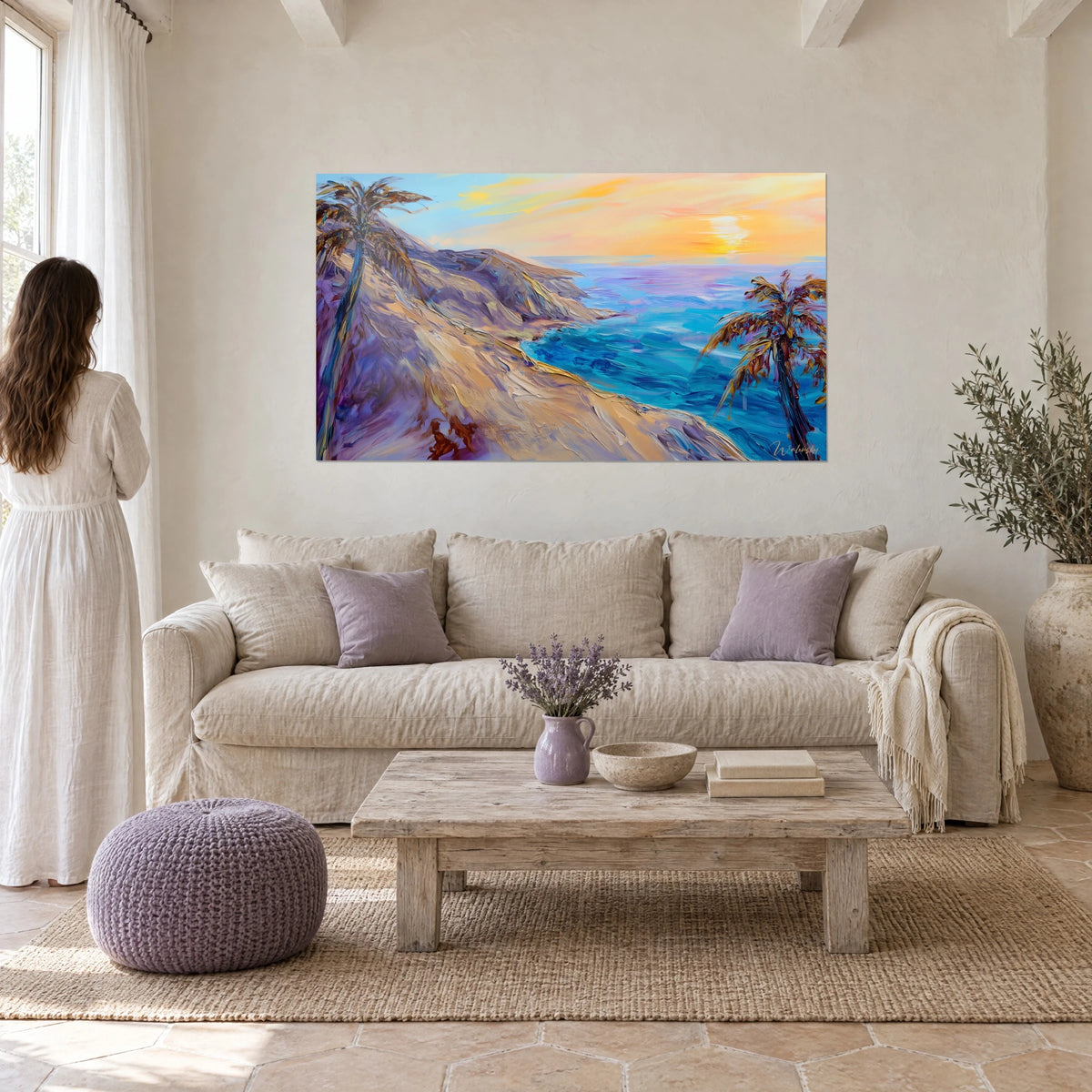 Schilderij van goudkleurige zandkliffen boven een turquoise zee, twee palmbomen en een oranje lucht, boven een bank in een lichte woonkamer