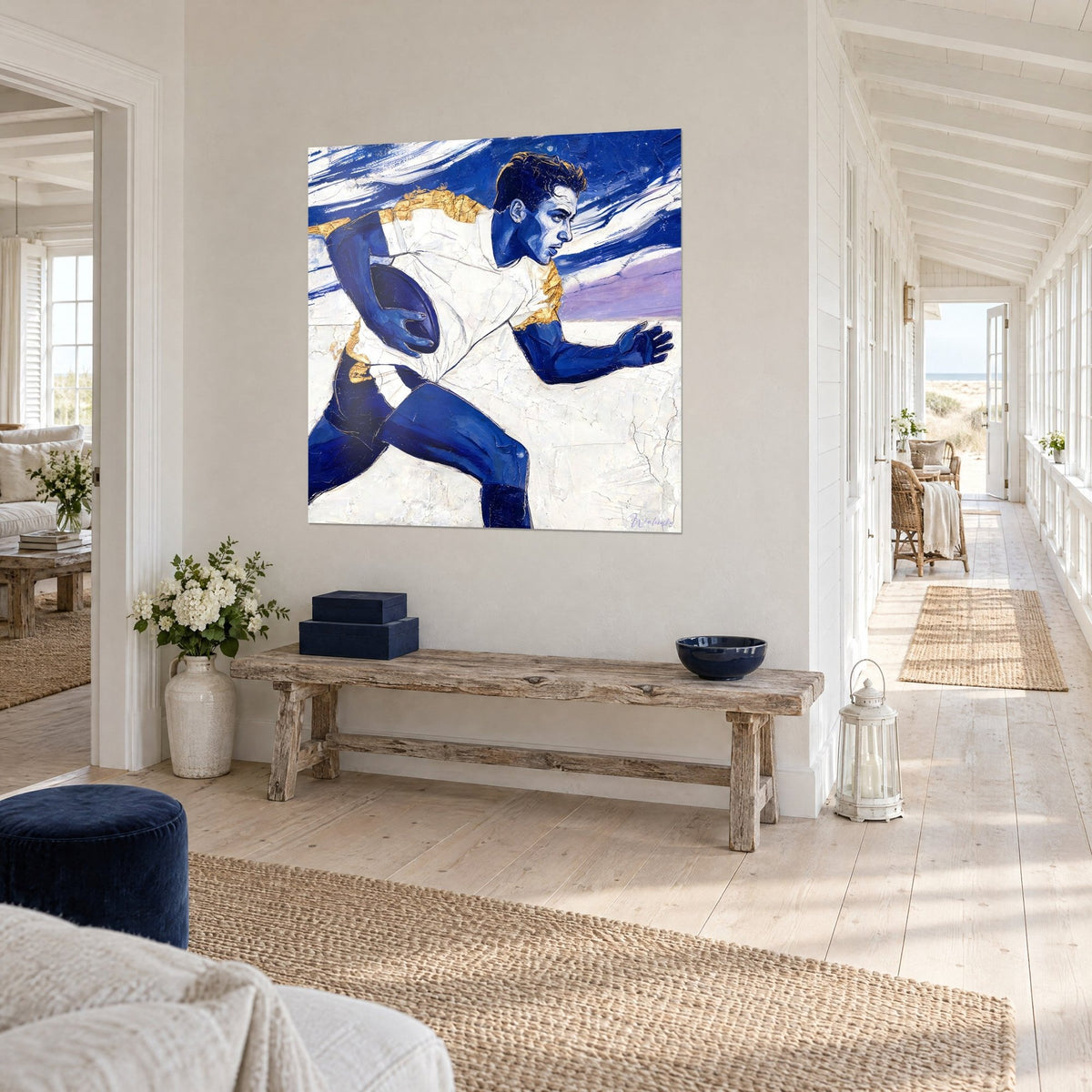 Rugbyman peint en bleu profond et blanc texturé, œuvre suspendue au-dessus d'un canapé dans un salon lumineux