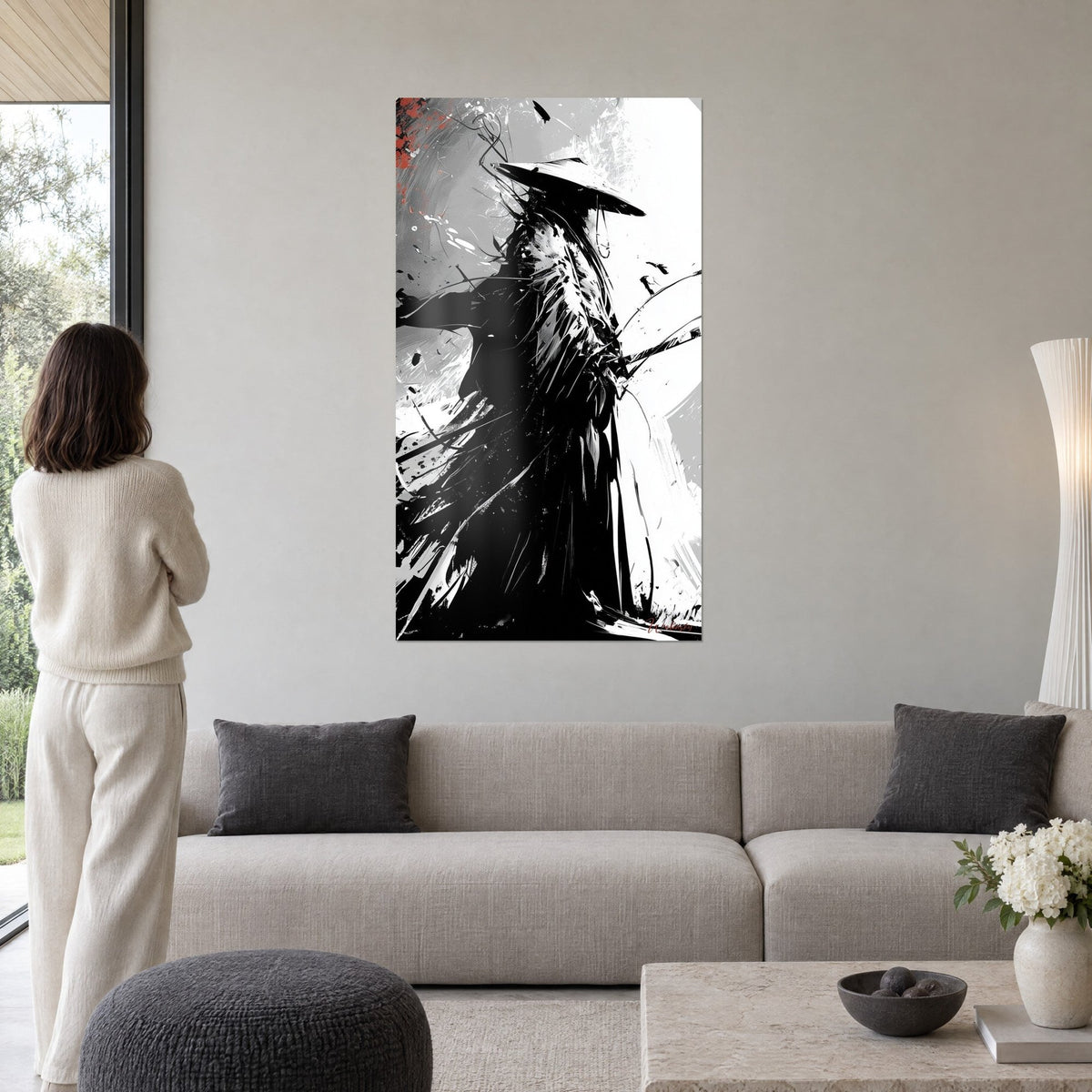 Wall art samurai with conical hat in black ink, grey splashes and a red accent, above a sofa in a bright living room