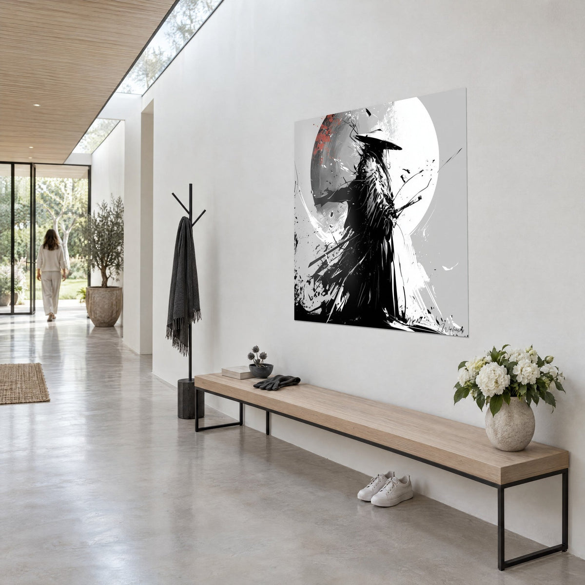 Wall art of a samurai in black ink, grey and white moon stained with red, paint splashes, hung on the wall of a light hallway in three-quarter view