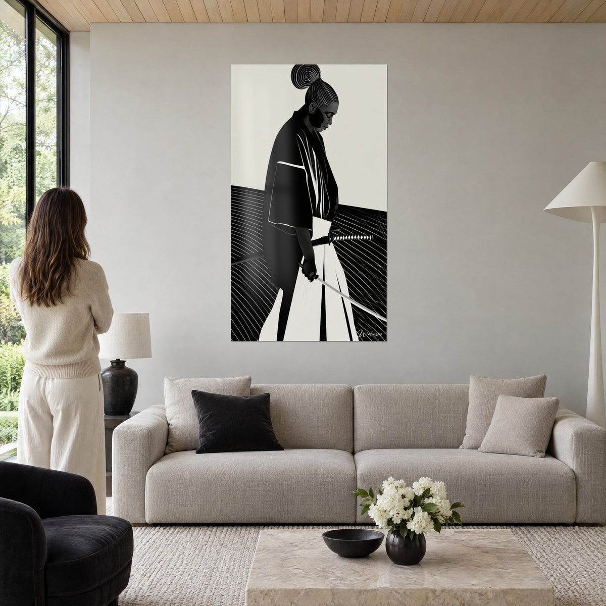 Wall art samurai with a spiral bun, black kimono and beige hakama, katana lowered, woman seen from behind, above a sofa in a bright living room