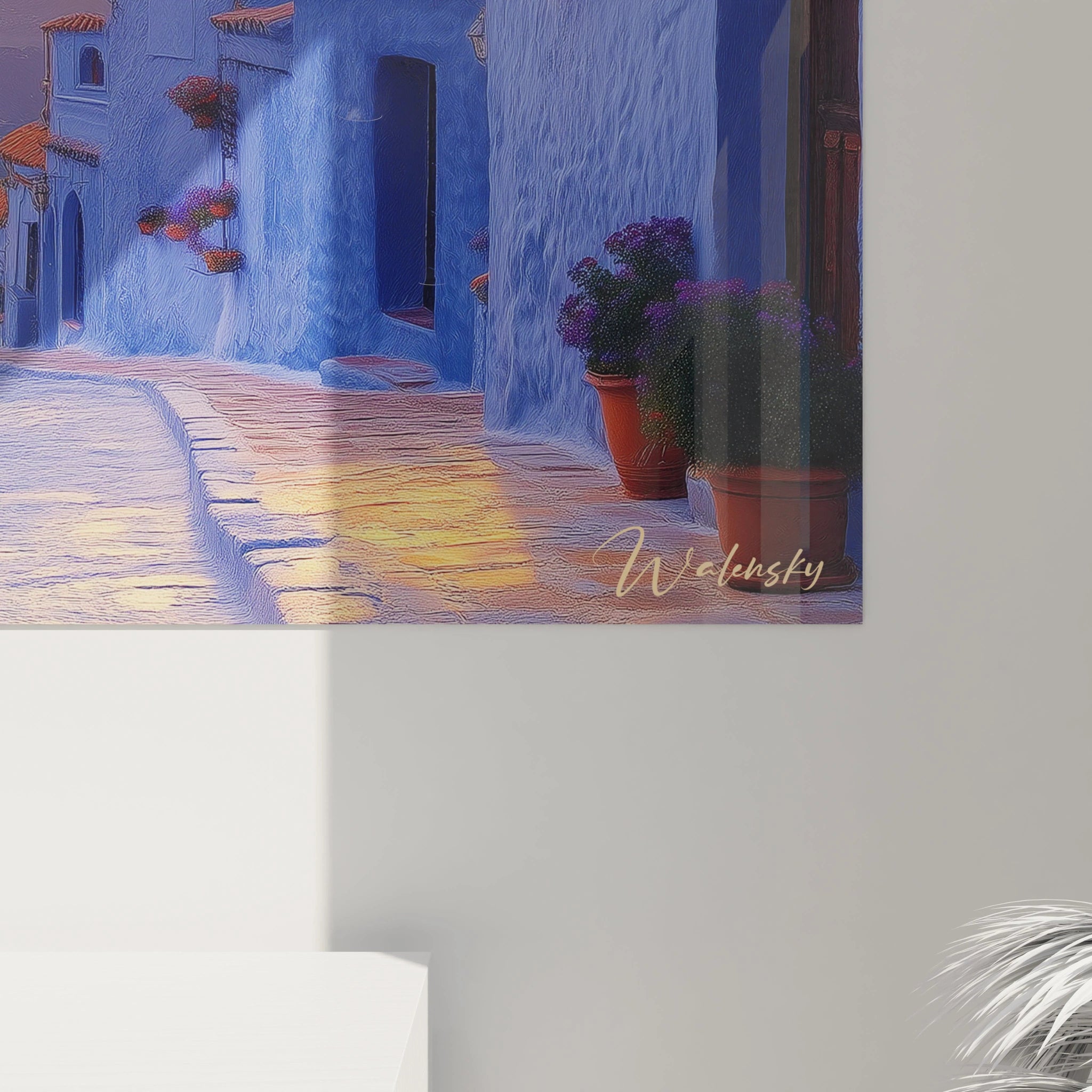 Tableau coucher de soleil présentant village traditionnel aux façades bleues texturées, toits terracotta visibles, lanternes murales décoratives et signature artistique discrète.