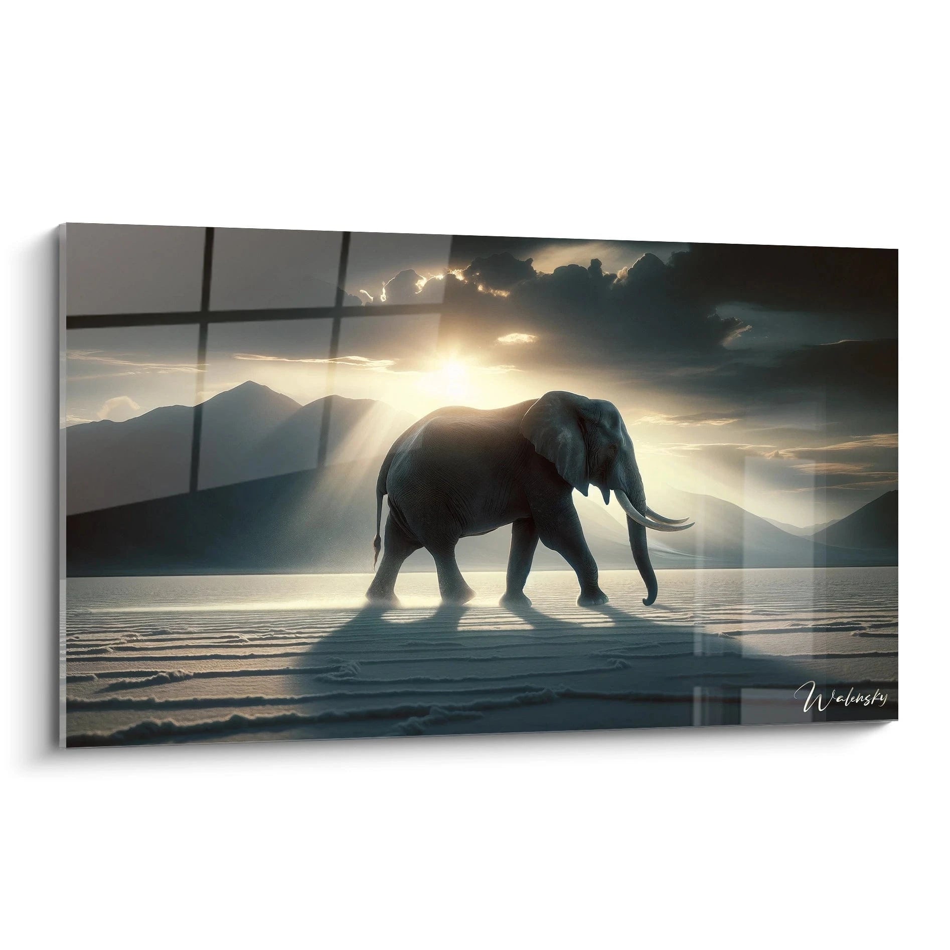 Un tableau d'animal représentant un éléphant marchant sur une surface plane et claire. La silhouette grise de l'animal se découpe contre un ciel dramatique où le soleil perce à travers des nuages sombres. Les rayons lumineux créent un effet de contre-jour sur les montagnes en arrière-plan et projettent l'ombre de l'éléphant sur le sol texturé.