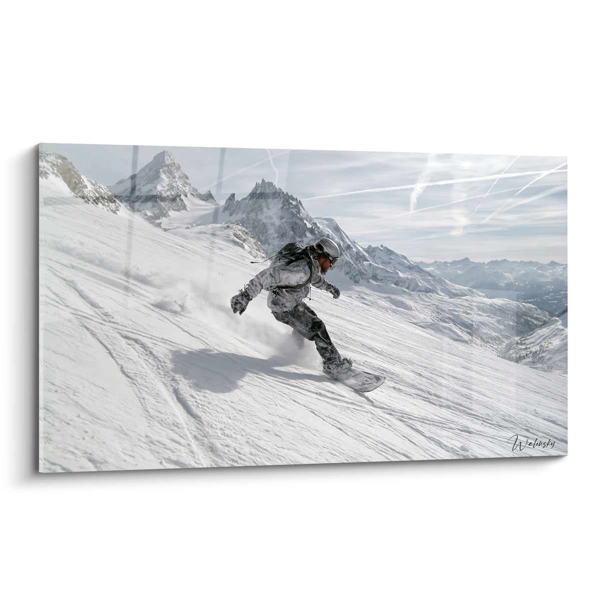 Snowboardeur en combinaison grise dévalant une pente blanche entre sommets alpins acérés