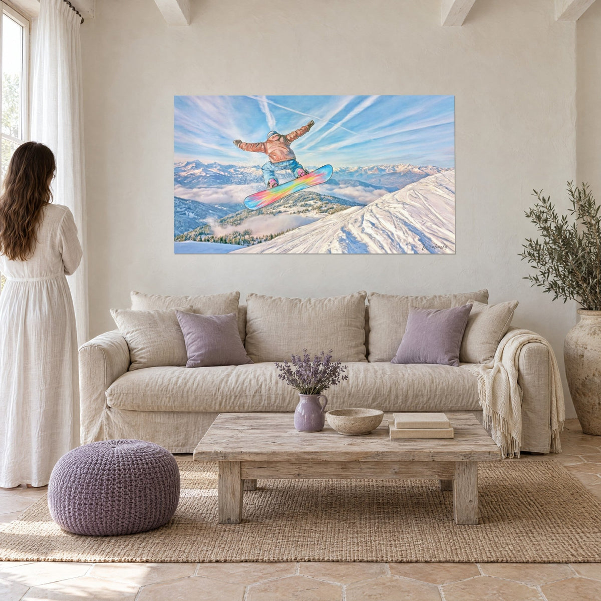 Schilderij van een snowboarder in de lucht, zalmkleurige jas en regenboogplank, blauwe lucht met wolkenstrepen, boven een bank in een lichte woonkamer
