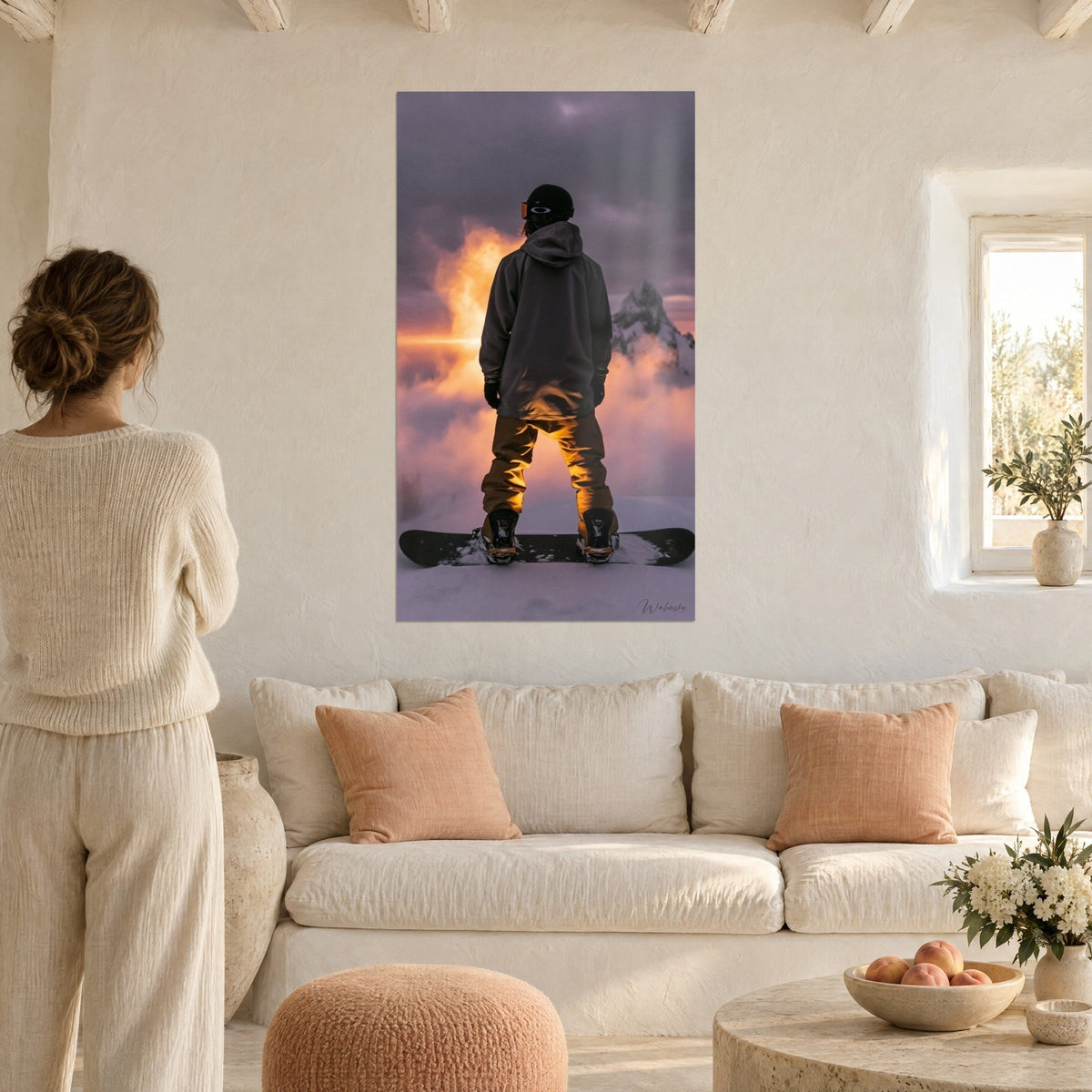 Tableau snowboardeur de dos en veste grise et pantalon ocre, nuages embrasés orange, au-dessus d'un canapé dans un salon lumineux