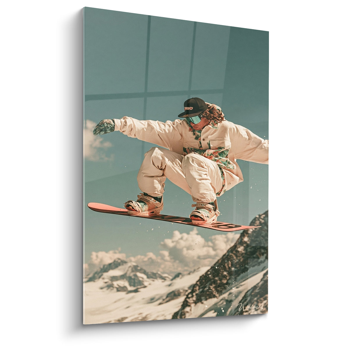 Snowboardeur en combinaison beige effectuant un saut, fond bleu-vert et sommets enneigés