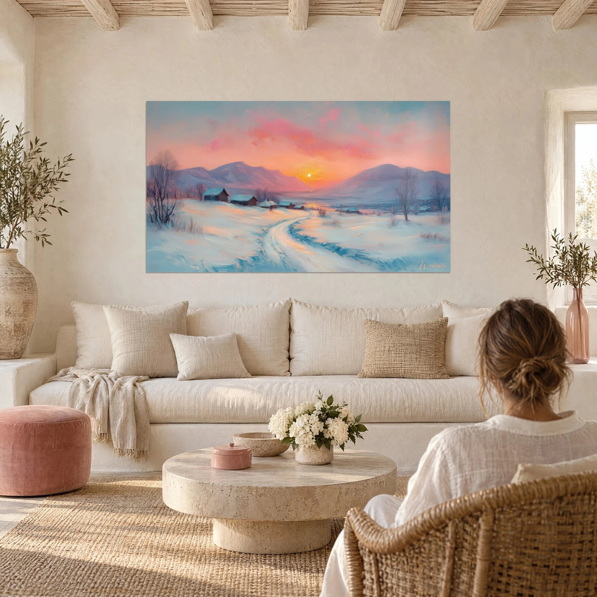 Cuadro de un caserío nevado bajo un cielo rosa y naranja, sol bajo entre montañas moradas, encima de un sofá en un salón luminoso