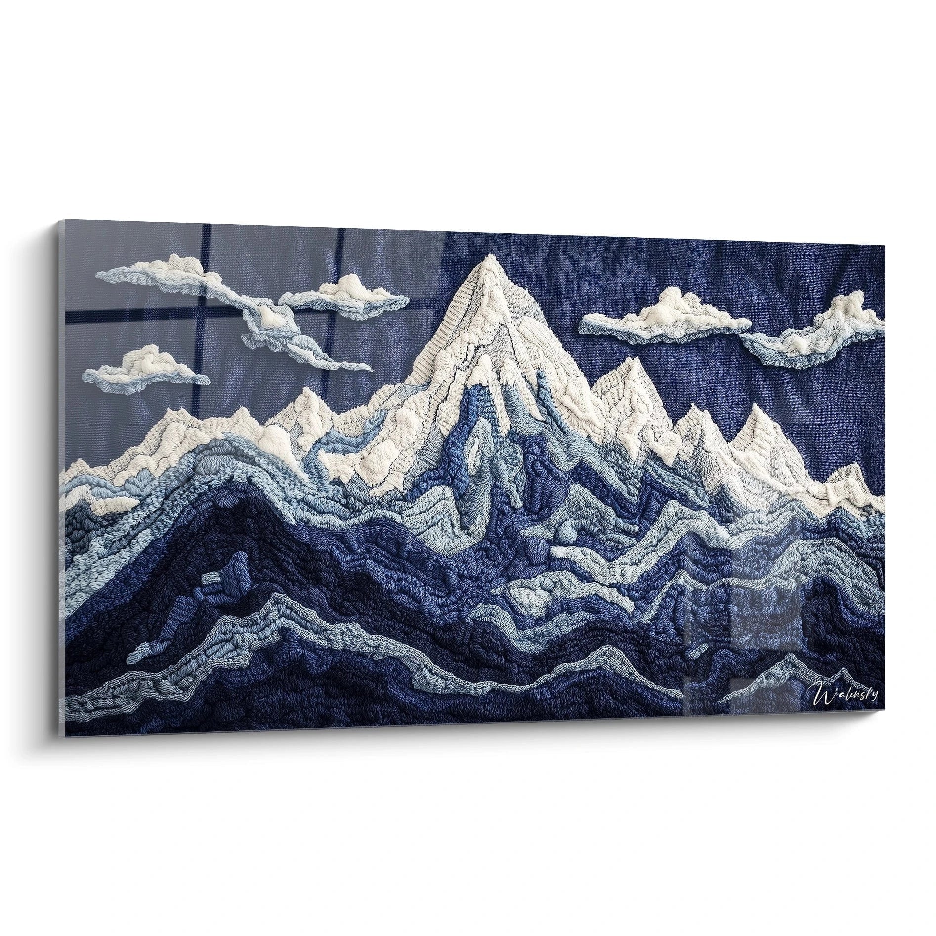 Un tableau textile représentant une chaîne de montagnes en relief, avec des sommets blancs enneigés et différentes nuances de bleu formant les vallées et les pentes, réalisé en technique de broderie et crochet sur fond bleu marine.