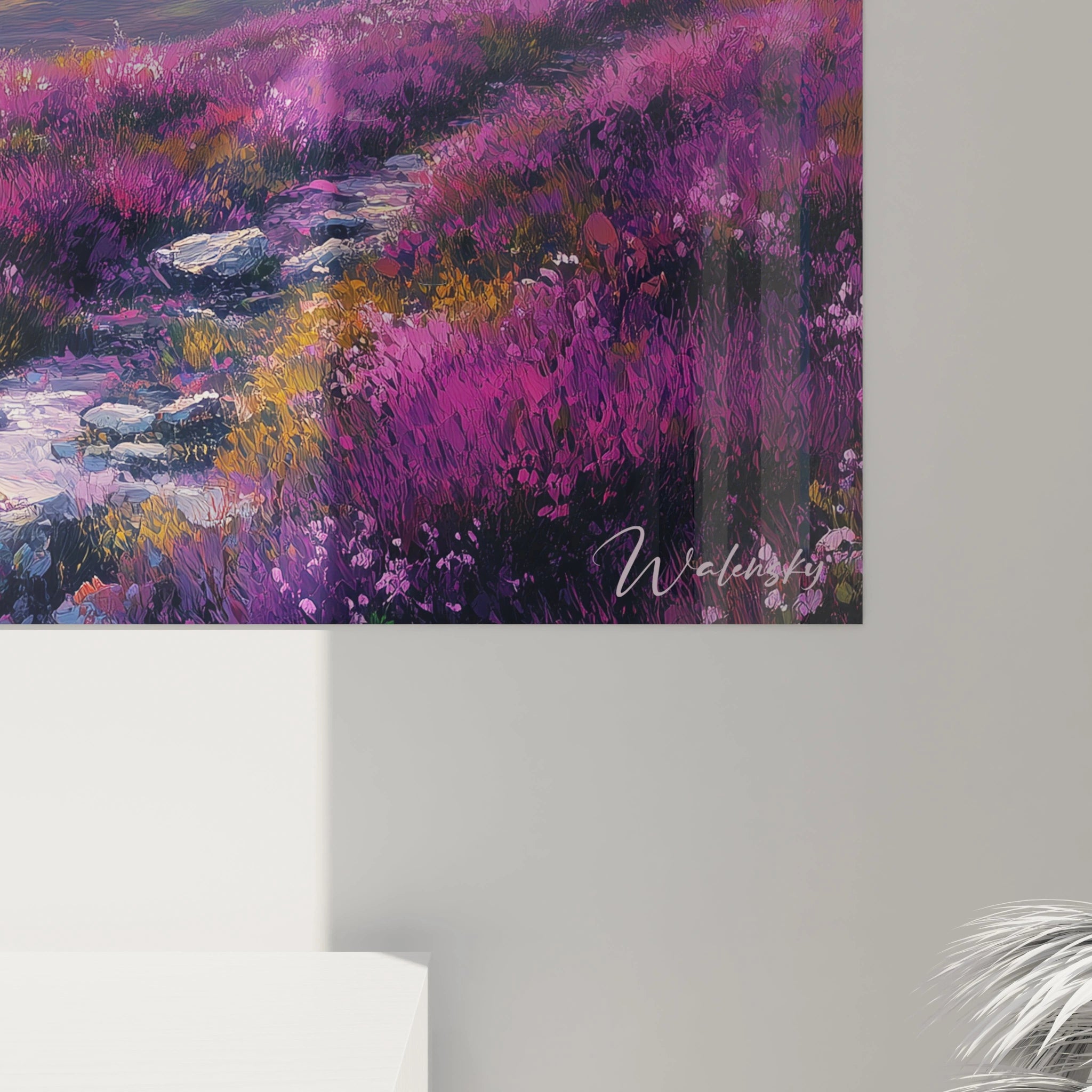 Ein Berggemälde mit einer Komposition von dicht blühenden Alpenwiesen in Violett, Rosa und Rot im Vordergrund, die sich bis zu blauen Bergketten unter einem Himmel in Orange- und hellem Gelbverlauf erstrecken.
