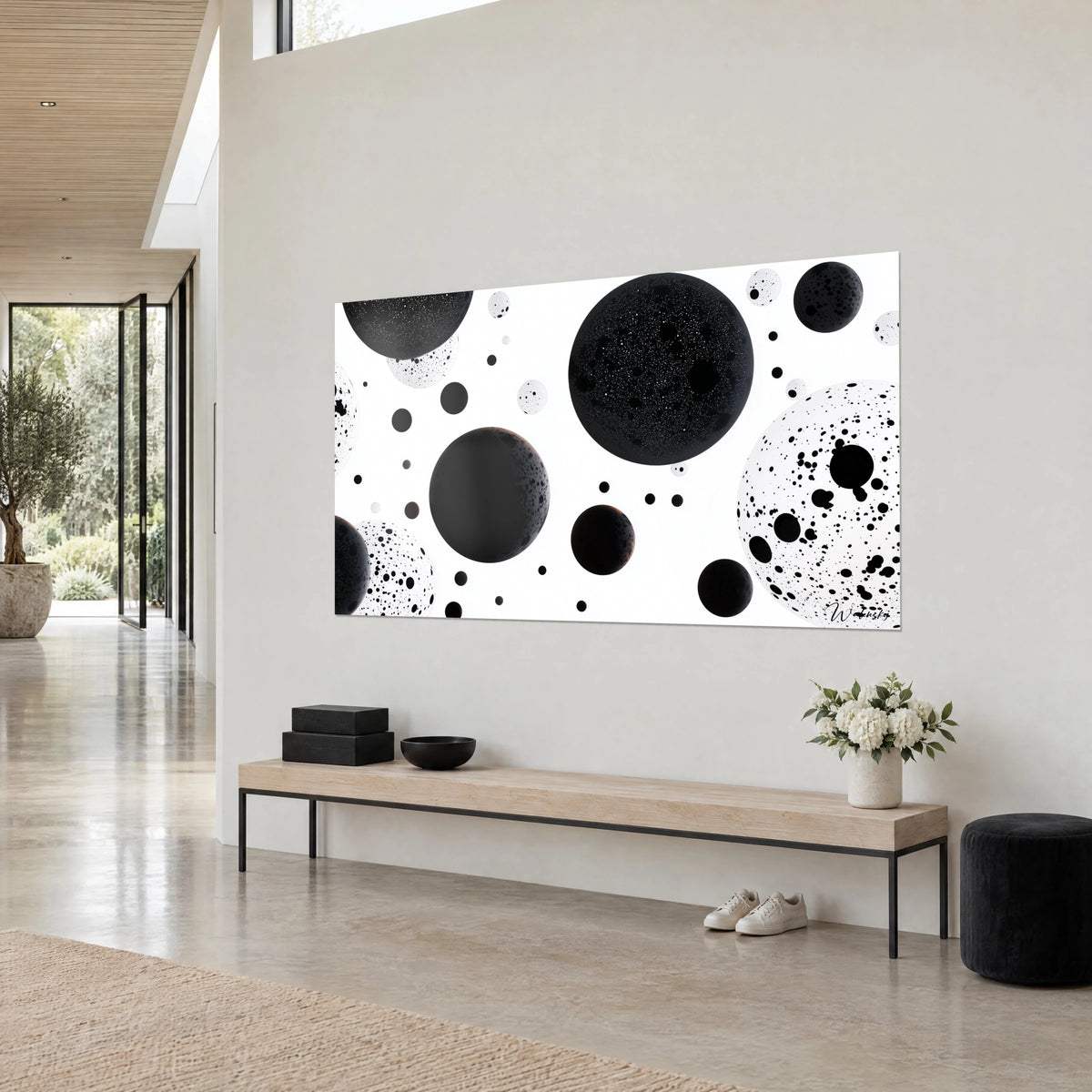 Quadro di pianeti d'inchiostro punteggiati di gocce, nero profondo e bianco puro, appeso in diagonale sopra una panca di legno chiaro