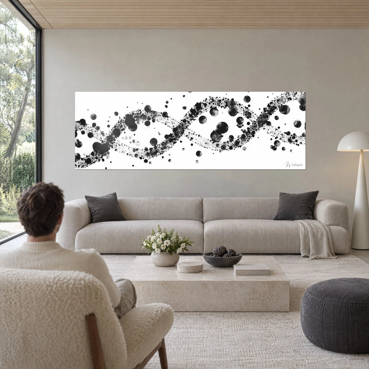 Tableau double hélice de taches d'encre noire sur fond blanc, bulles grises en suspension, au-dessus d'un canapé dans un salon lumineux