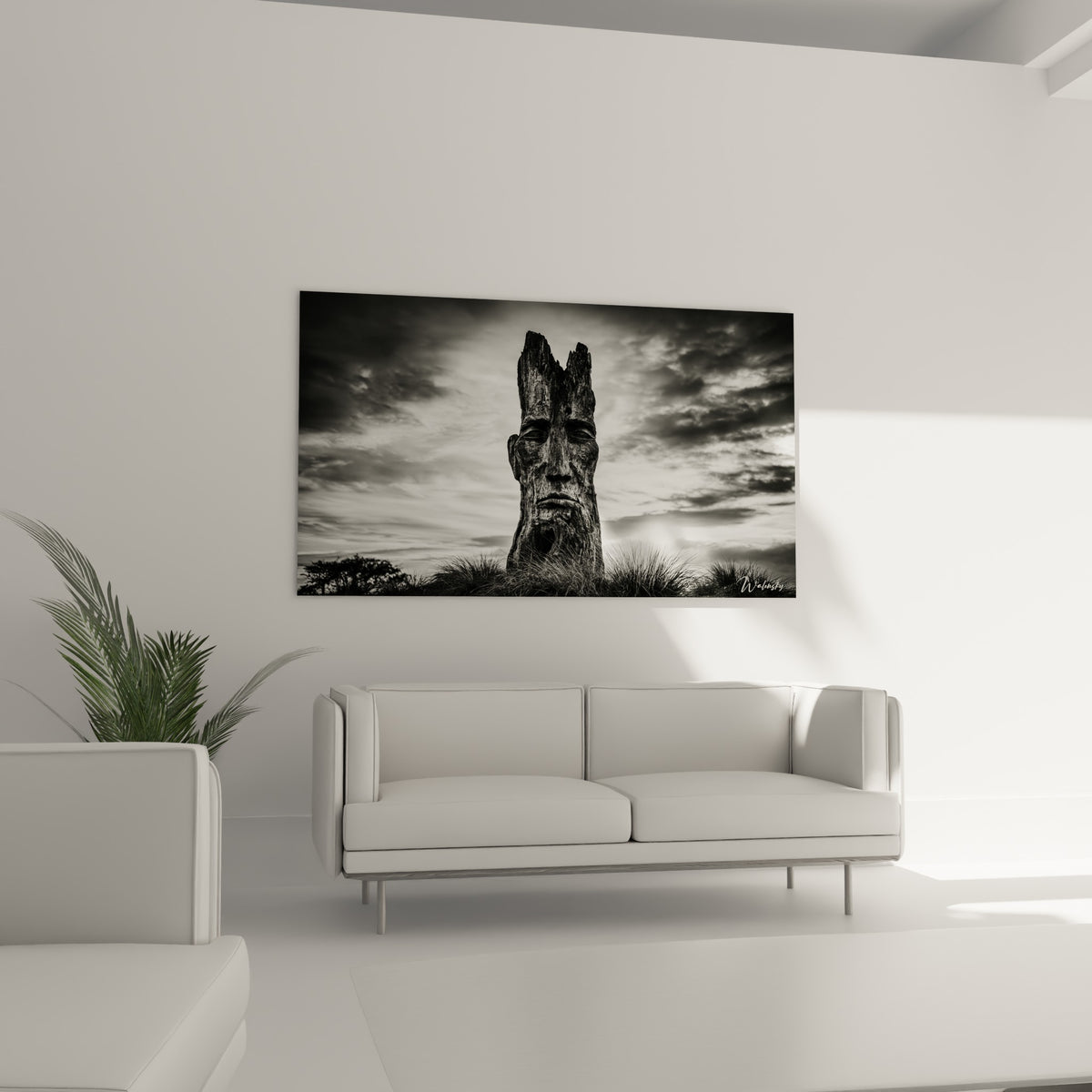 Statue ancestrale au visage anthracite se détachant sur un ciel blanc, au-dessus d'un canapé dans un salon lumineux