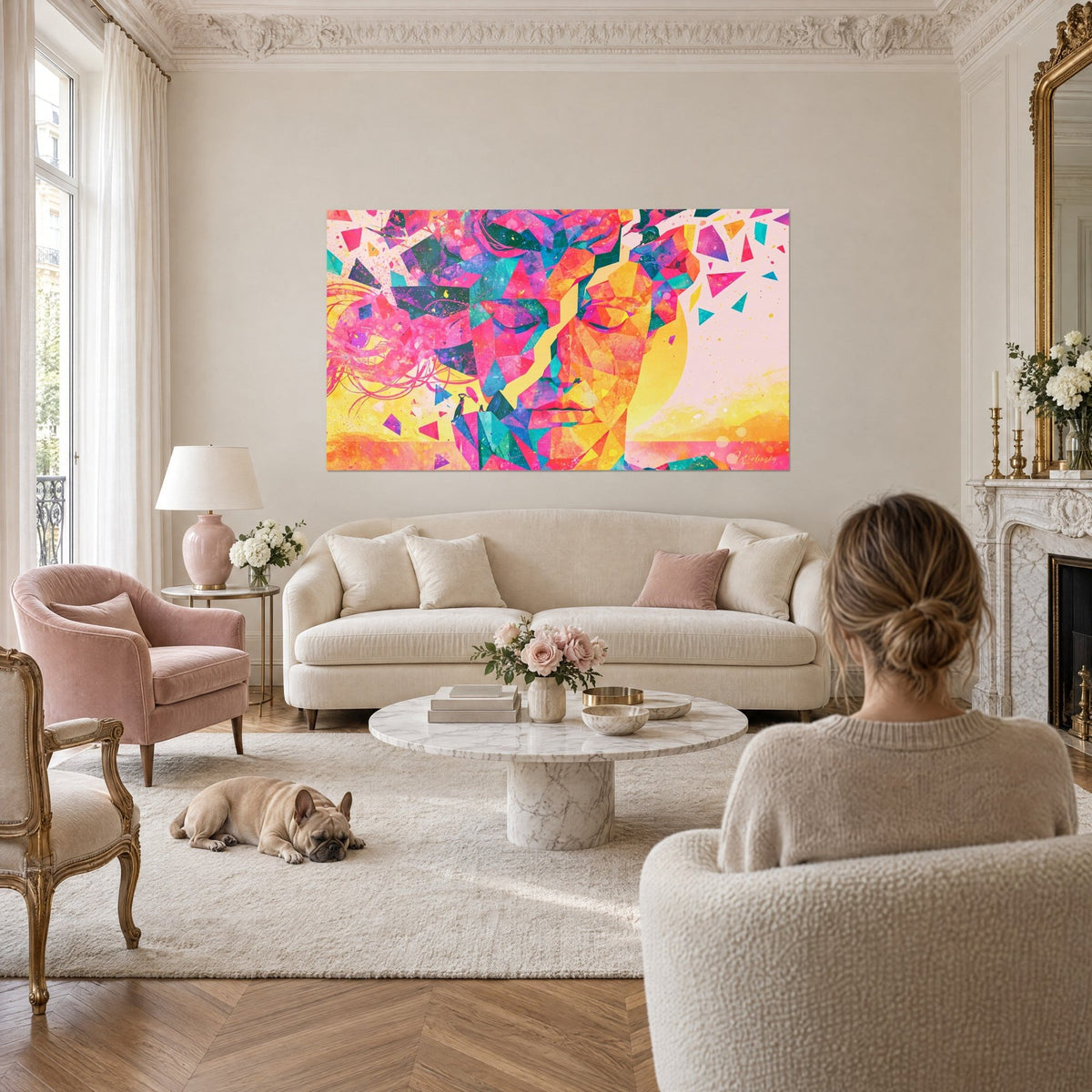 Tableau visage de femme en facettes roses et dorées, paupières closes, éclats flottants, au-dessus d'un canapé dans un salon lumineux