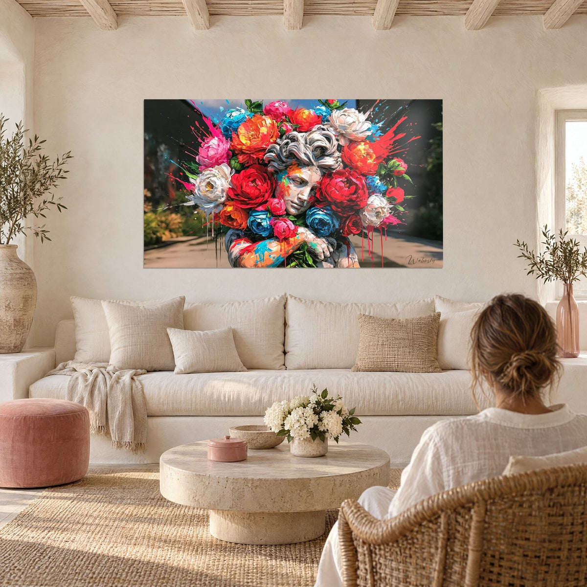 Tableau buste de marbre blanc noyé de pivoines rouges et bleues, éclaboussures roses, au-dessus d'un canapé dans un salon lumineux