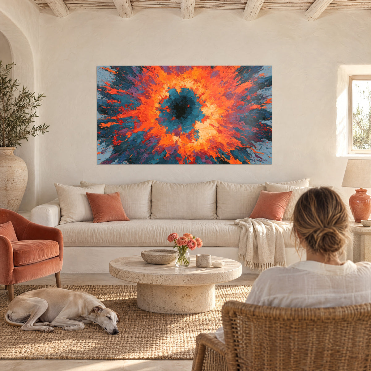Tableau œil cosmique orange et bleu pétrole, femme de dos et lévrier couché, au-dessus d'un canapé dans un salon lumineux