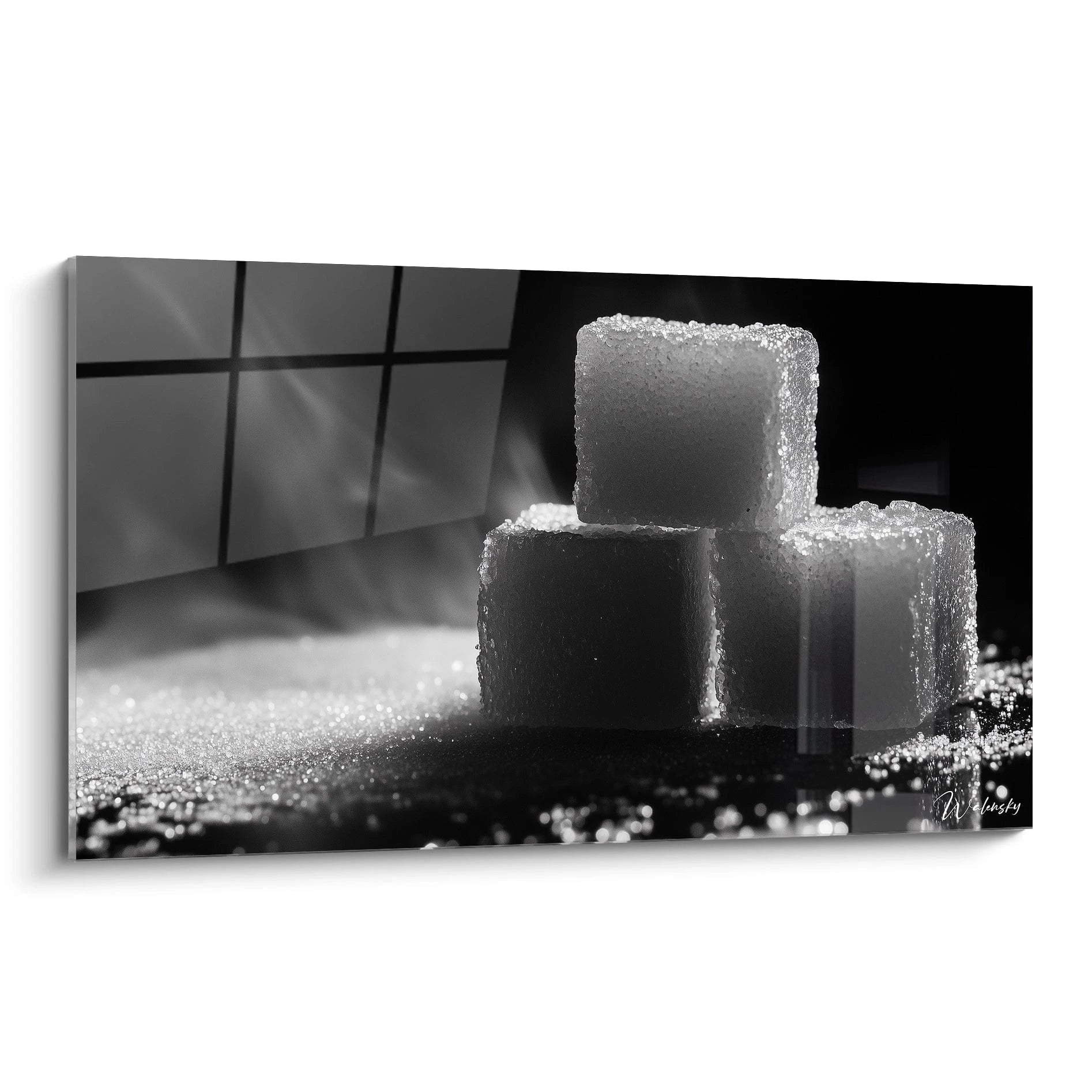 Un tableau sucre en noir et blanc mettant en scène trois cubes de sucre empilés, illuminés par une lumière rasante. Les textures granuleuses et les ombres profondes renforcent le contraste visuel.