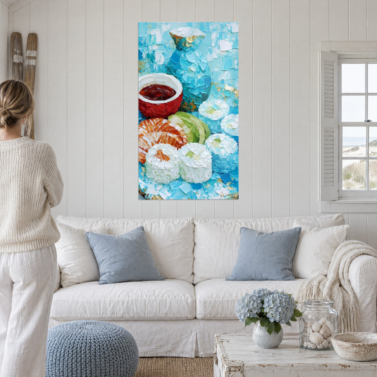 Wall art of white maki rice beside a turquoise carafe and a red bowl of soy sauce, above a sofa in a bright living room