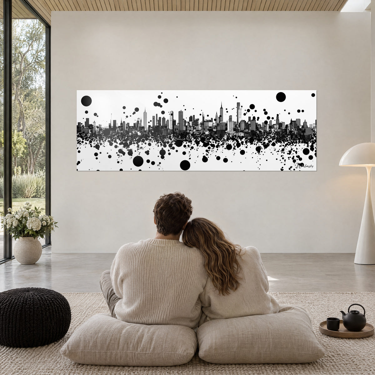 Quadro città verticale di Manhattan in nero su bianco, getti di vernice e dischi neri, coppia di spalle seduta su pouf beige