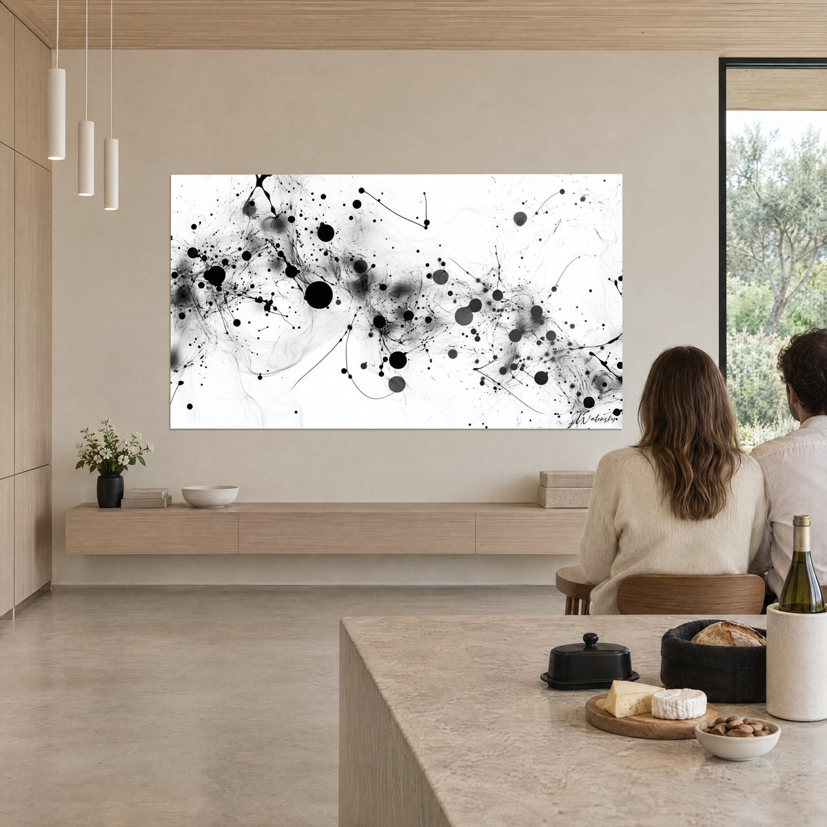 Tableau synapses noires et grises sur fond blanc pur, admirées par deux convives de dos, derrière un îlot en pierre beige clair