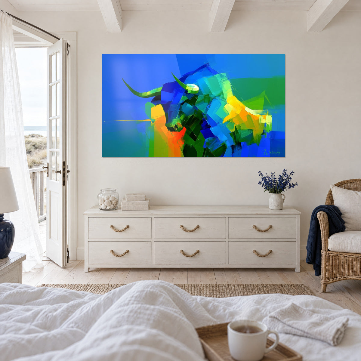Cuadro de un búfalo en planos de azul celeste y amarillo limón, colgado sobre una cama en un dormitorio luminoso abierto a las dunas