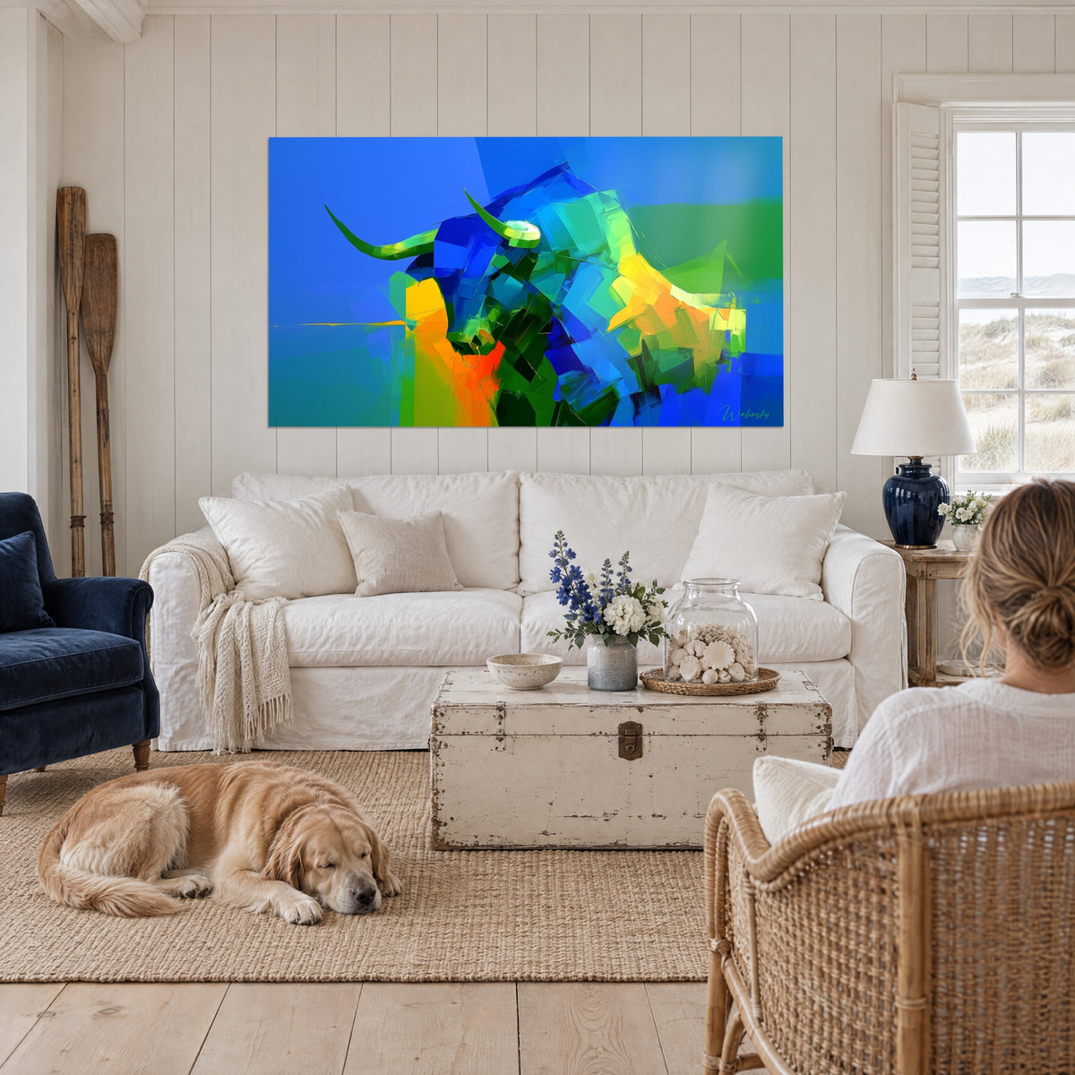 Cuadro de un toro cubista con cuernos verdes, azul cobalto y naranja vivo, encima de un sofá en un salón luminoso