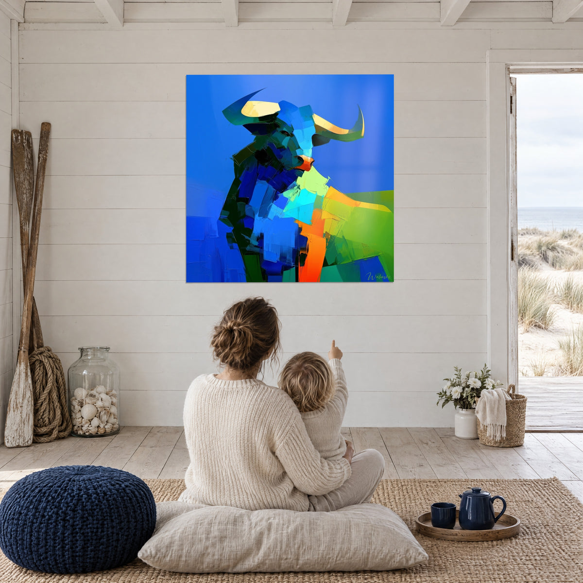 Cuadro gran toro pop azul eléctrico y verde esmeralda, una madre y su hijo de espaldas sentados en un puf, duna al fondo
