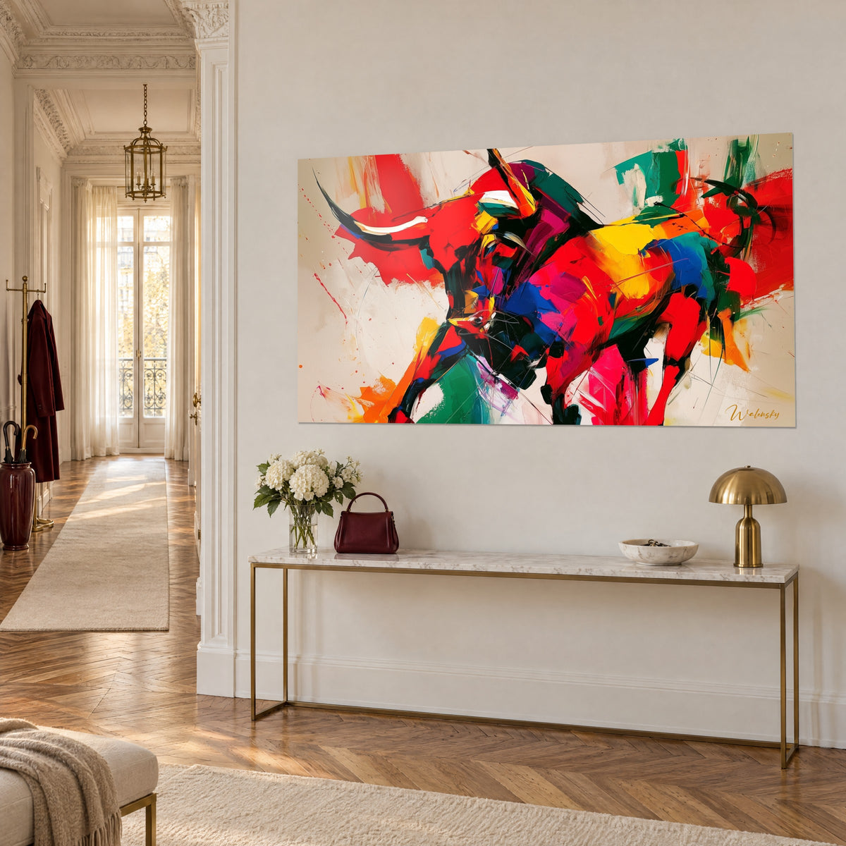 Tableau bovin furieux aux coups de spatule rouges, bleus et jaunes, accroché sur un mur crème au-dessus d'une console dorée