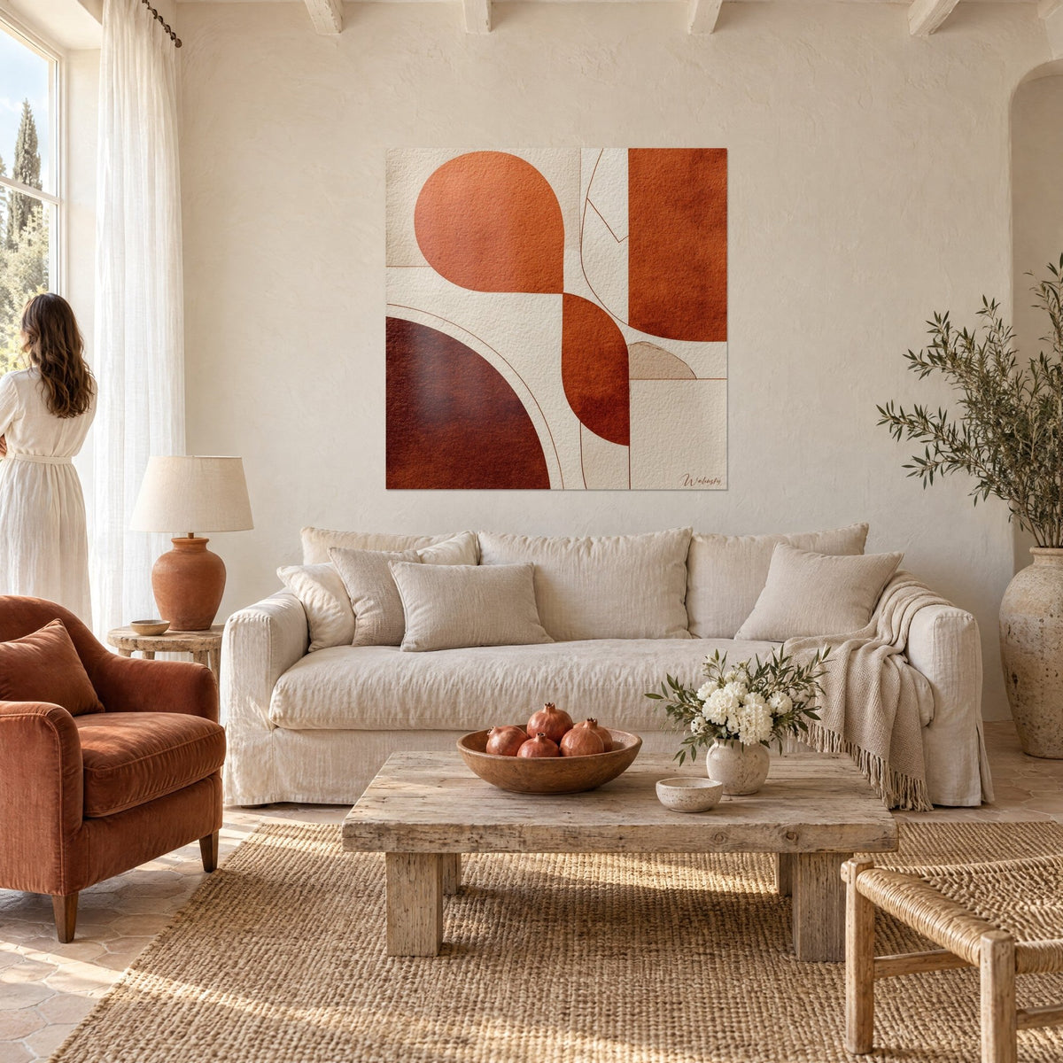 Tableau formes courbes rouille et beige sable, goutte orange et demi-disque brun, femme de dos, au-dessus d'un canapé dans un salon lumineux