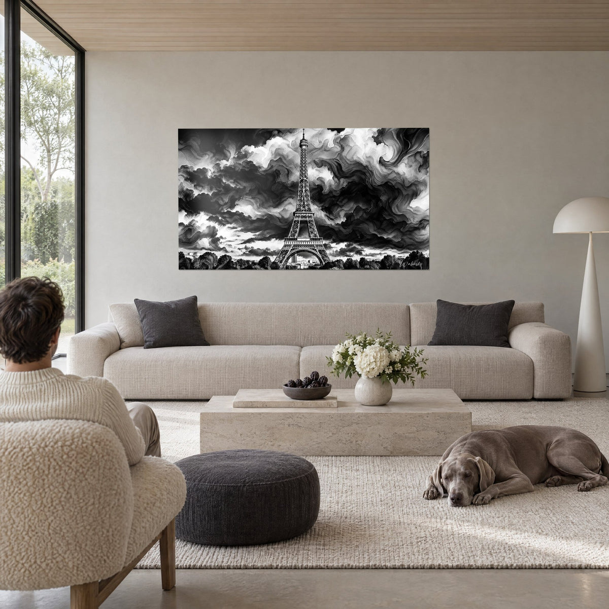 Tableau Tour Eiffel en noir et blanc sous nuages tourbillonnants, gris perle et noir d'encre, Weimaraner couché, au-dessus d'un canapé dans un salon lumineux