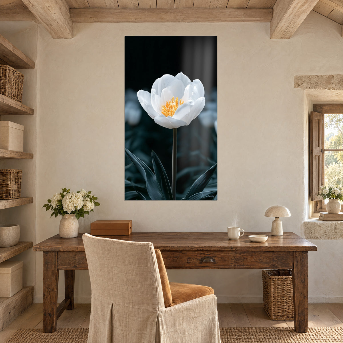 Tableau tige élancée portant une fleur blanche au centre orangé, fond noir et feuilles ardoise, au-dessus d'un bureau en bois