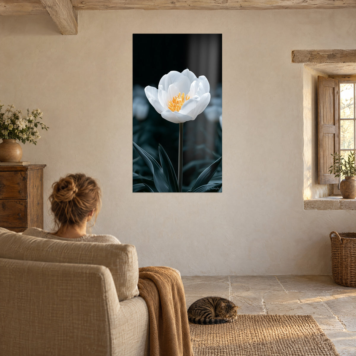 Tableau tulipe immaculée aux étamines jaune d'or, feuillage bleu-gris flou, une femme de dos et un chat tabby dans un salon en pierre