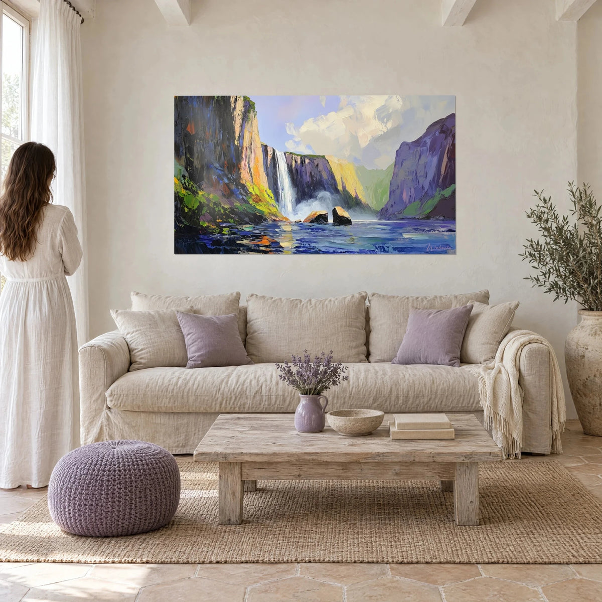 Quadro cascata che precipita da una scogliera viola in un lago blu, rocce ocra al centro, sopra un divano in un soggiorno luminoso