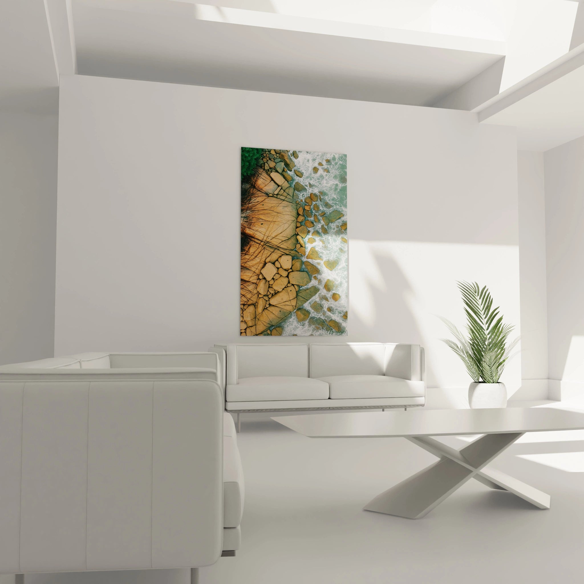 Un tableau vue aérienne montrant l'interface entre terre et mer, avec des formations rocheuses beiges structurées par des lignes sombres naturelles. La végétation verte dense borde la côte tandis que l'eau turquoise et blanche s'enroule autour des rochers épars.