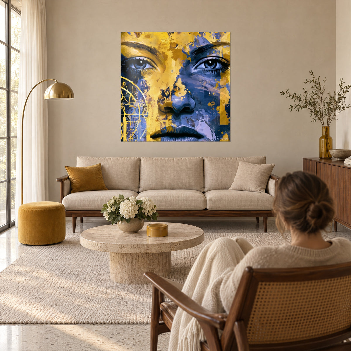 Tableau portrait de femme aux yeux profonds, jaune moutarde et bleu marine, arches dorées, au-dessus d'un canapé dans un salon lumineux