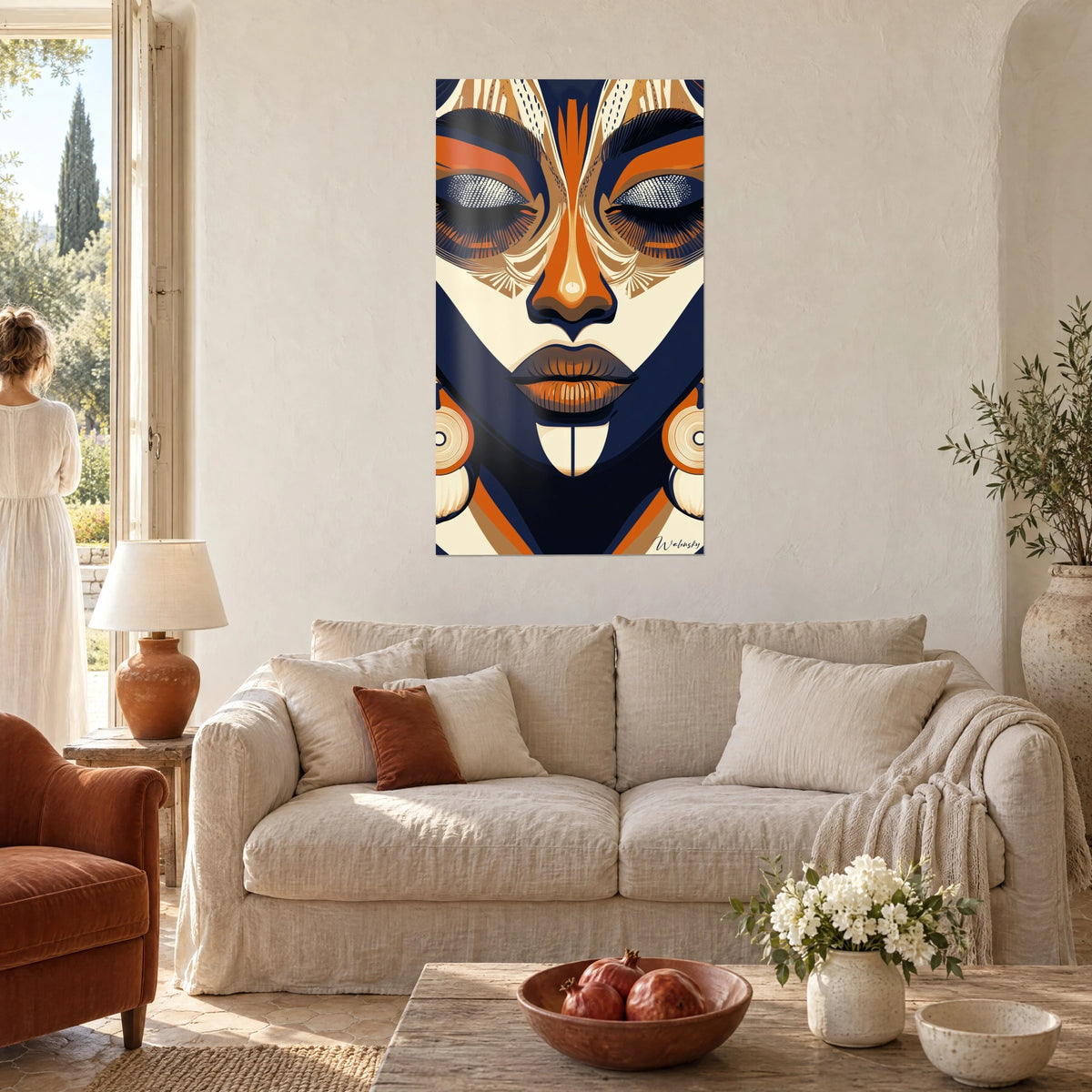 Cuadro rostro africano de párpados cerrados, naranja quemado y azul noche, pendientes redondos, encima de un sofá en un salón luminoso