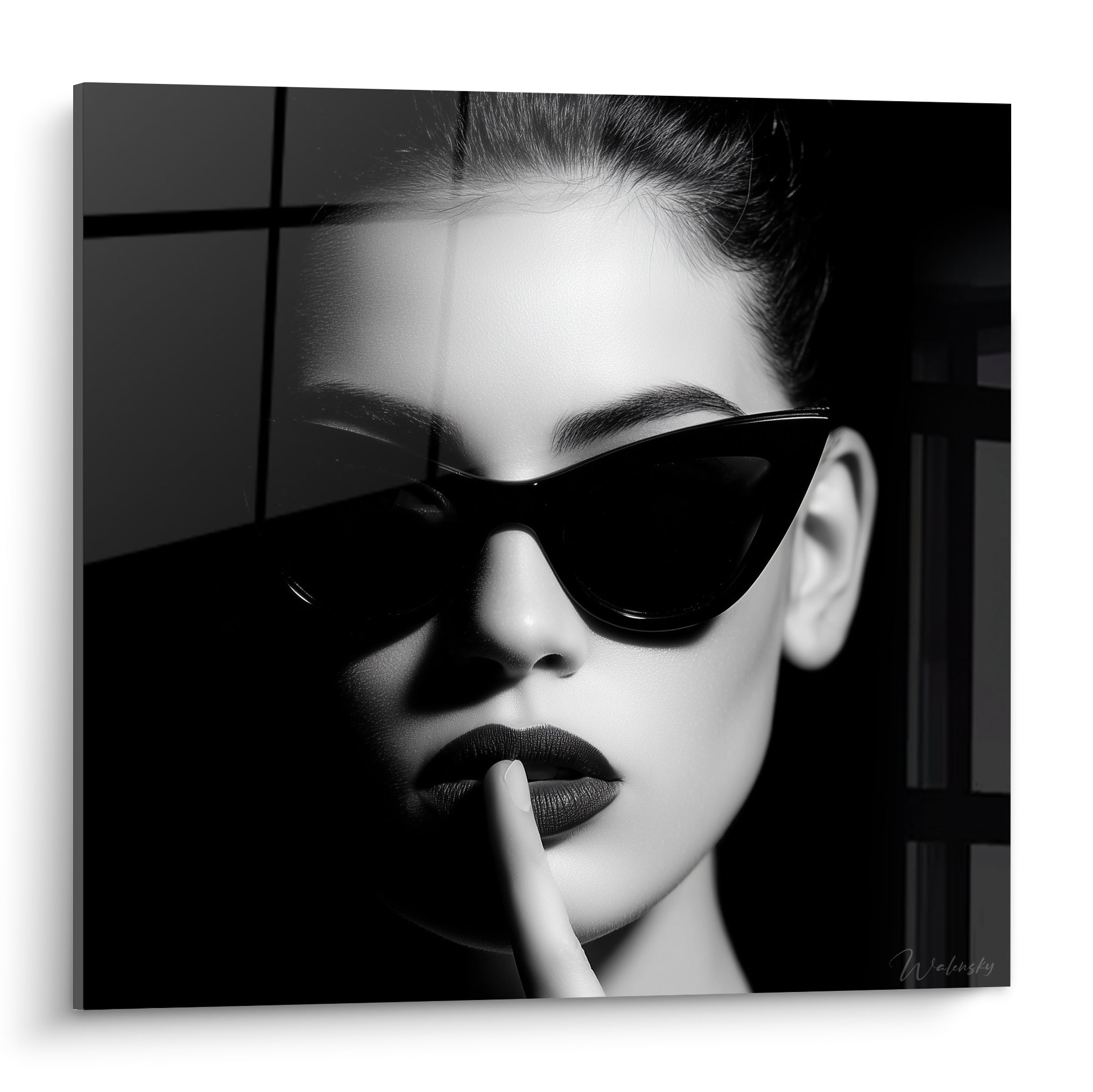 Visage féminin aux lunettes cat-eye noires et lèvres gris foncé, doigt posé sur la bouche