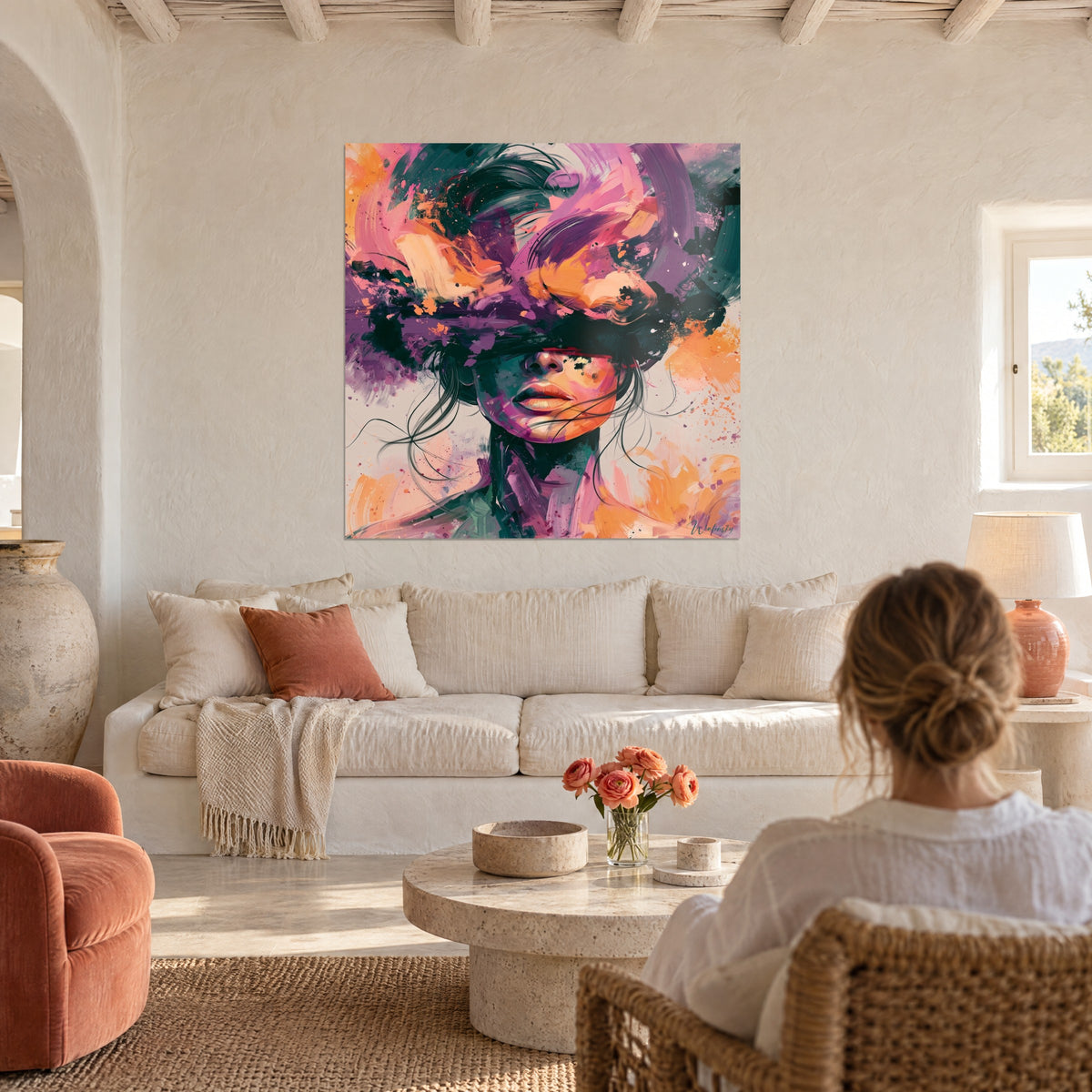 Tableau visage de femme aux yeux bandés de coups de pinceau violets et orange, mur chaux blanc, au-dessus d'un canapé dans un salon lumineux