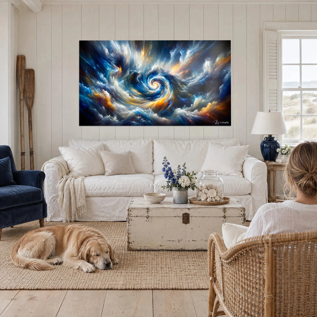 Wall art of a cosmic spiral in cobalt blue and golden ochre, two people seen from behind, a reclining retriever, above a sofa in a bright living room