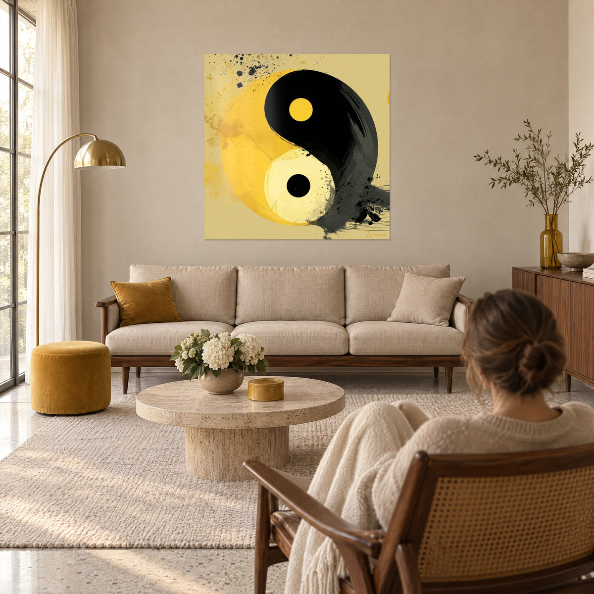 Schilderij yin yang symbool in mosterdgeel en zwart, inktspatten, een vrouw van achteren boven een bank in een lichte woonkamer