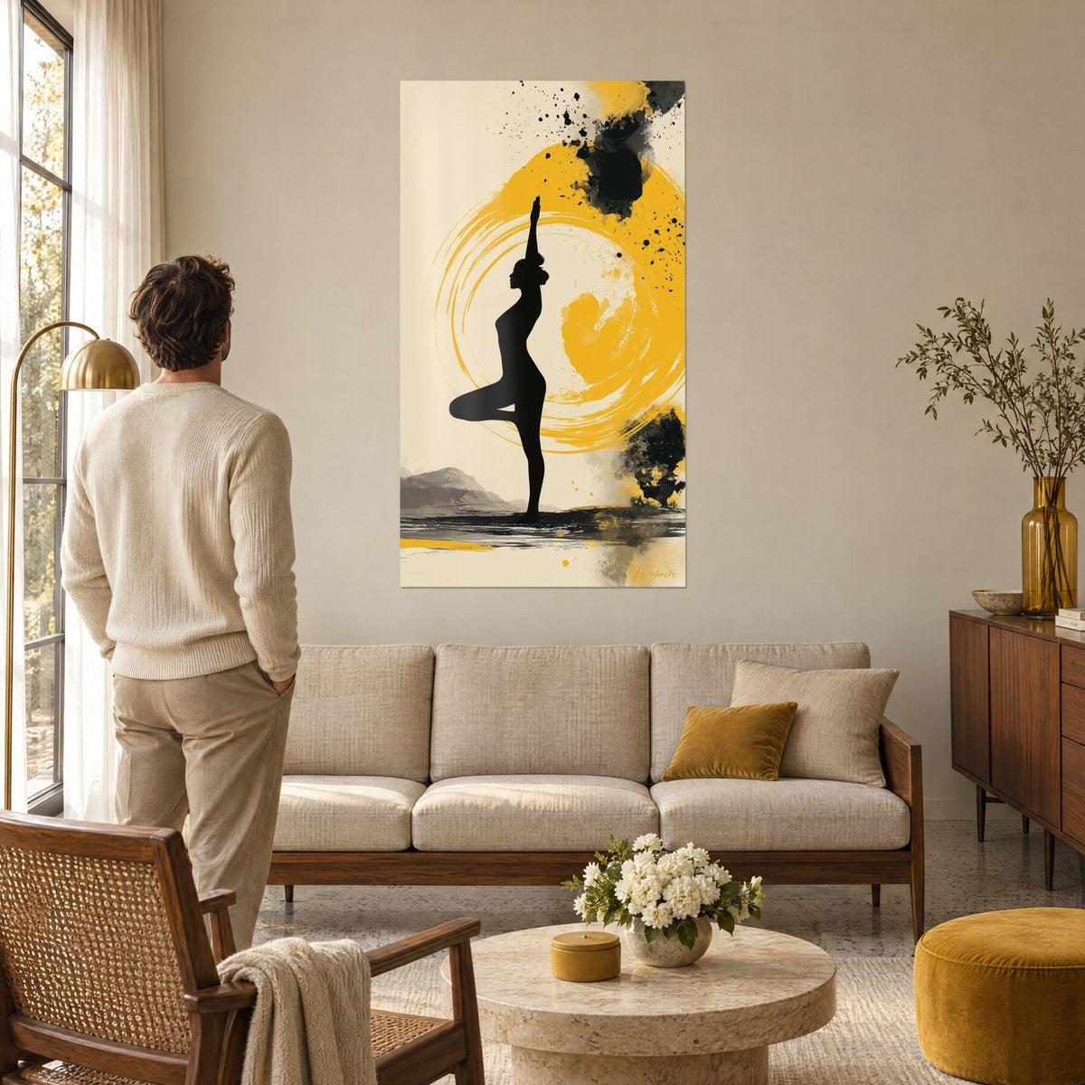 Wall art black silhouette in tree pose, golden ochre halo and ink splatters, hanging above a sofa in a bright living room