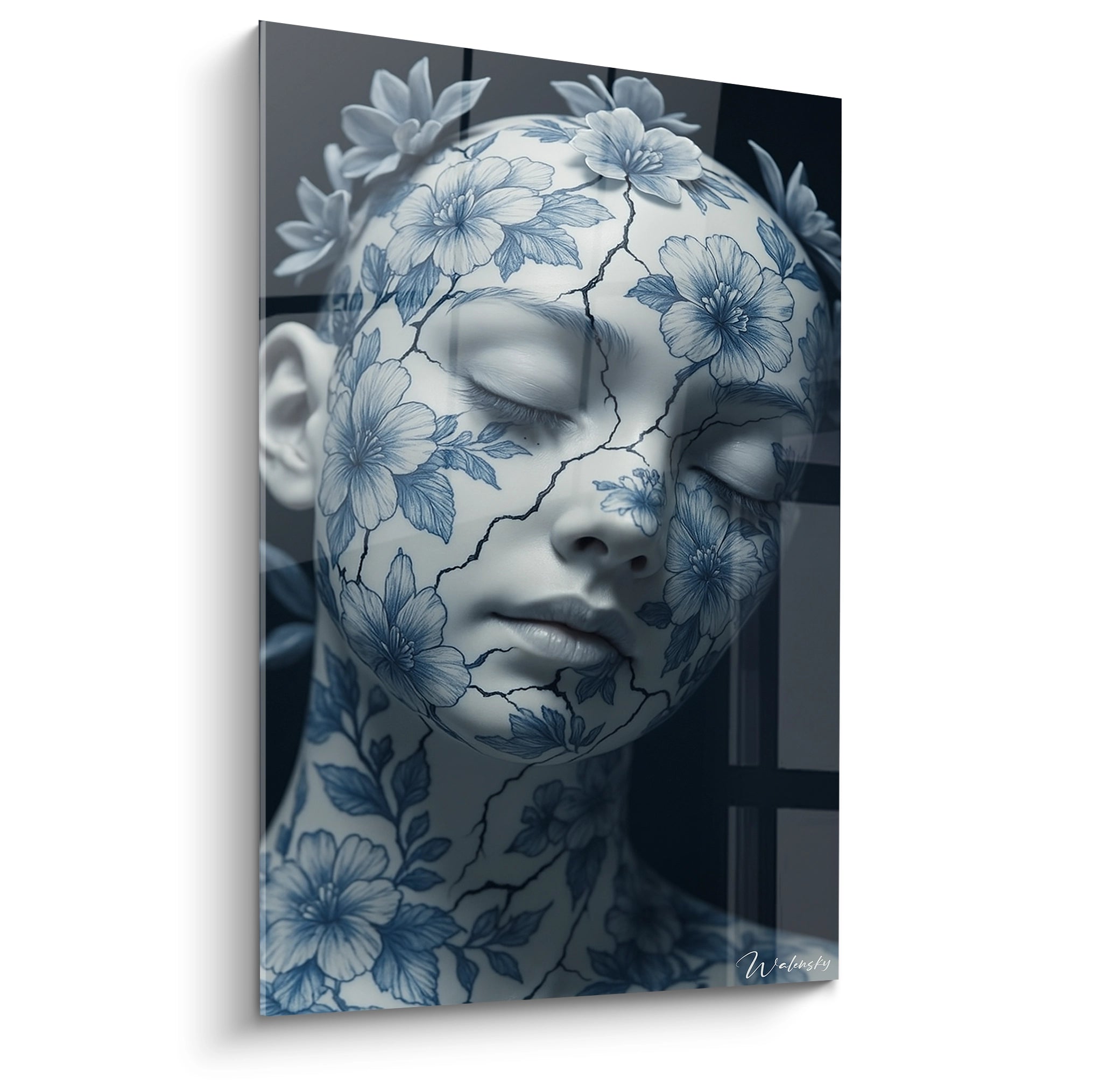Un tableau porcelaine représentant un visage féminin aux yeux clos, orné de motifs floraux bleus sur fond blanc craquelé. Les fissures noires serpentent à travers la surface, créant un contraste saisissant avec la délicatesse des fleurs bleues et le teint blanc immaculé.