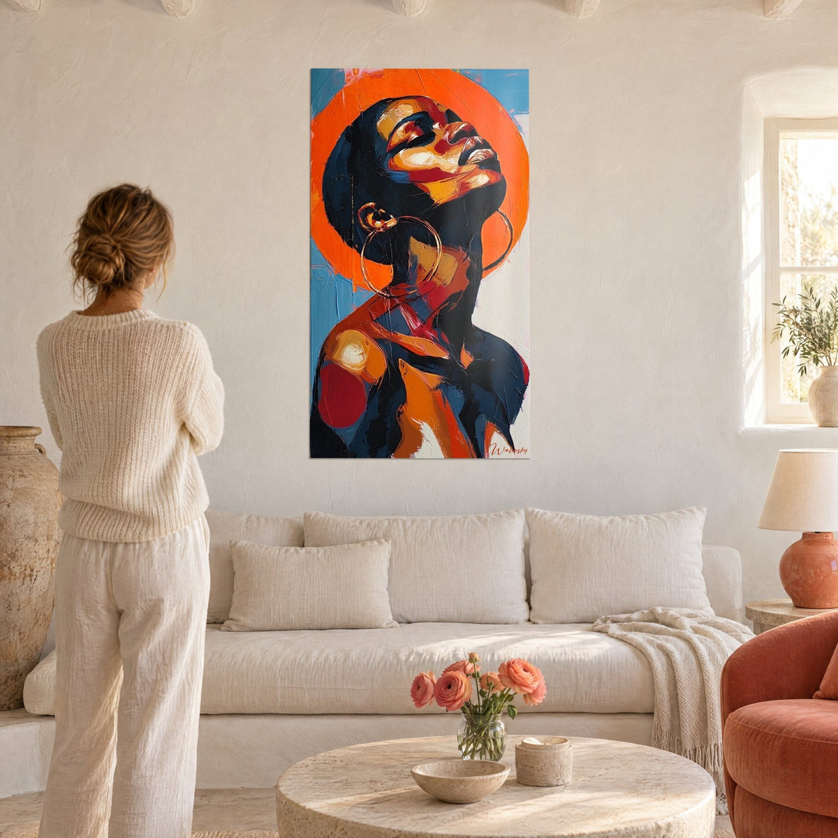 Tableau portrait de femme au visage levé, halo orange vif et peau ocre, bleu nuit, femme de dos, au-dessus d'un canapé dans un salon lumineux