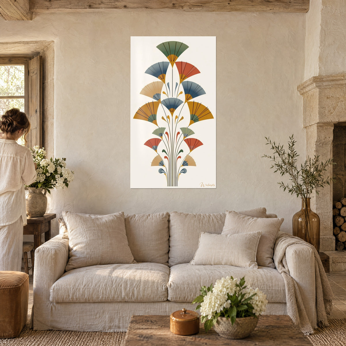 Quadro di ventagli Art Déco in ocra e verde salvia, donna di spalle, pareti in pietra, sopra un divano in un soggiorno luminoso