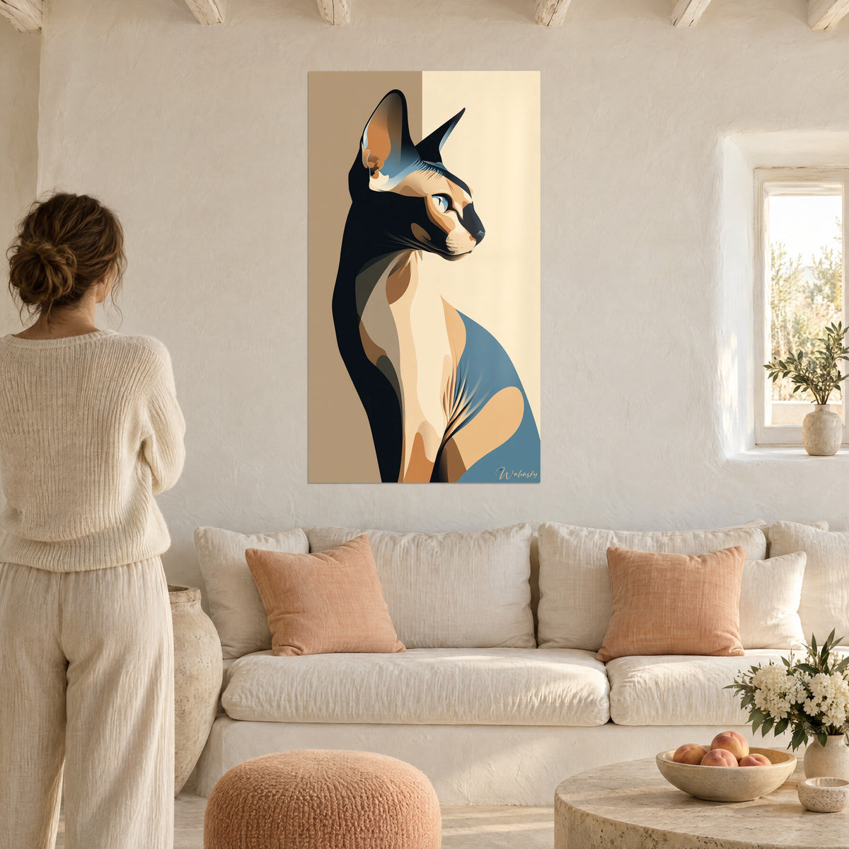 Cuadro gato esfinge de perfil, ocre y azul acero sobre fondo arena, visto de espaldas, encima de un sofá en un salón luminoso